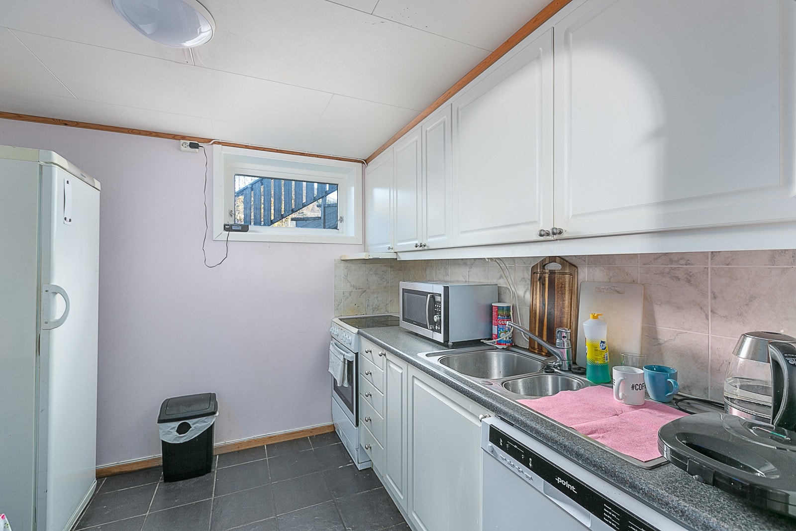 Kjøkkenet i kjellerleiligheten har frittstående hvitevarer. Galleribilde