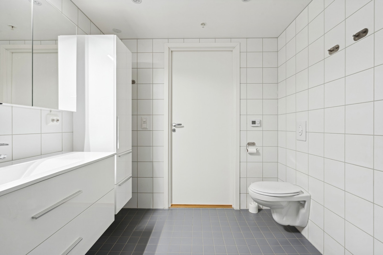 Her er opplegg for vaskemaskin og innredning med skuffer i tillegg til speilskap på veggen for ekstra oppbevaring Galleribilde