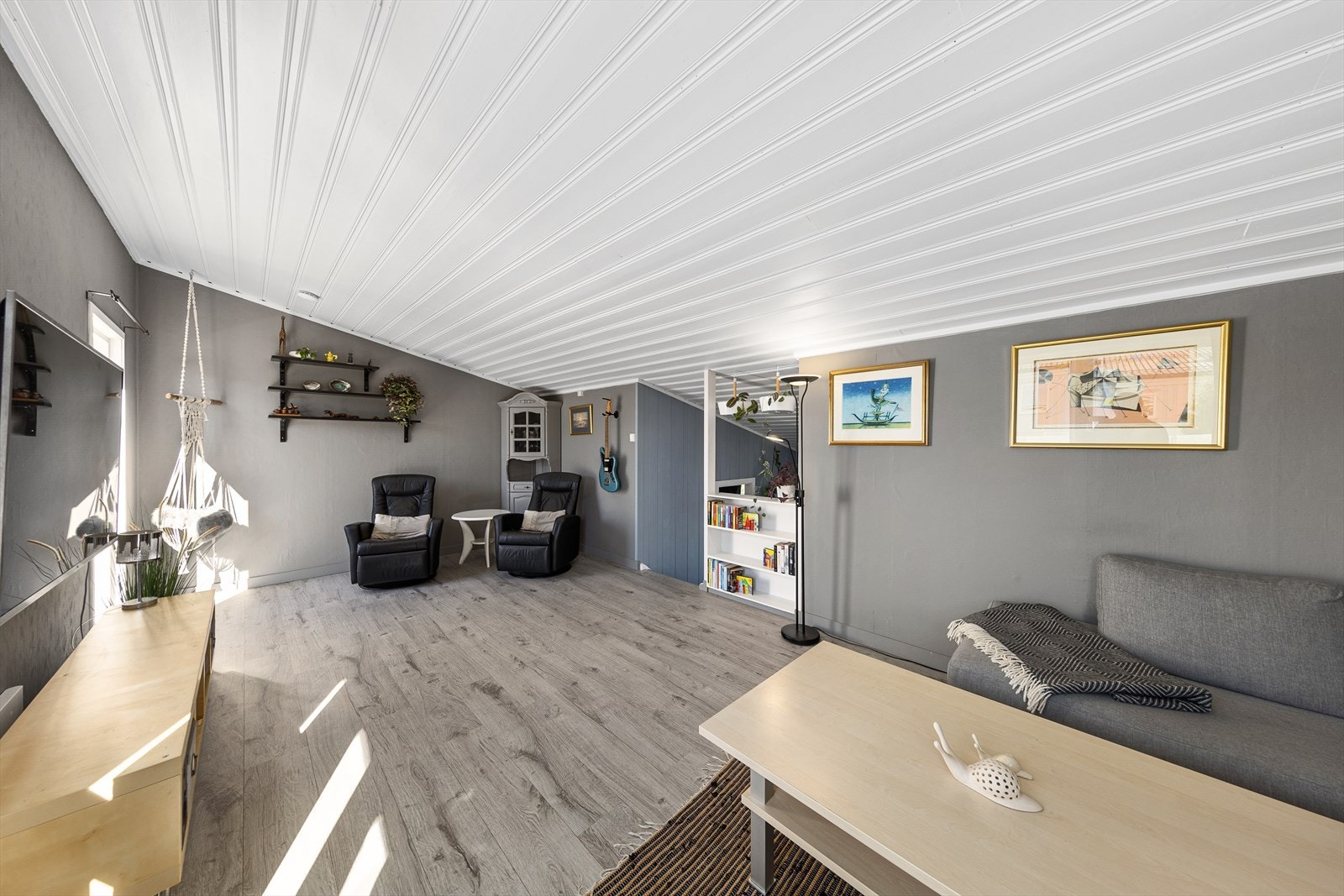 Stor stue med lyse overflater, store vindusflater og utgang til sørvestvendt veranda. Galleribilde