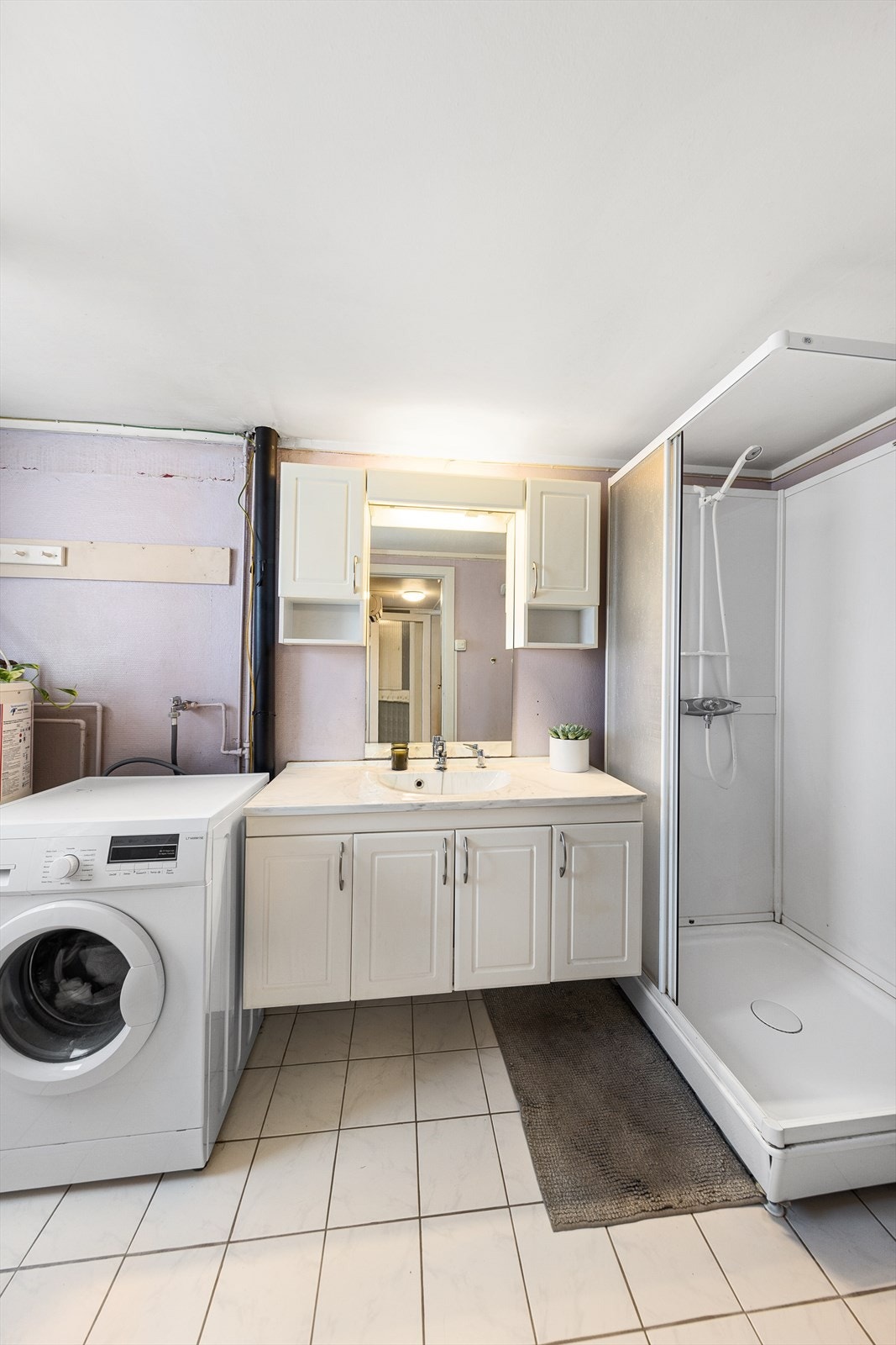 Badet er eldre og har flislagt gulv med varmekabler og plater med malt strie på vegger. Galleribilde
