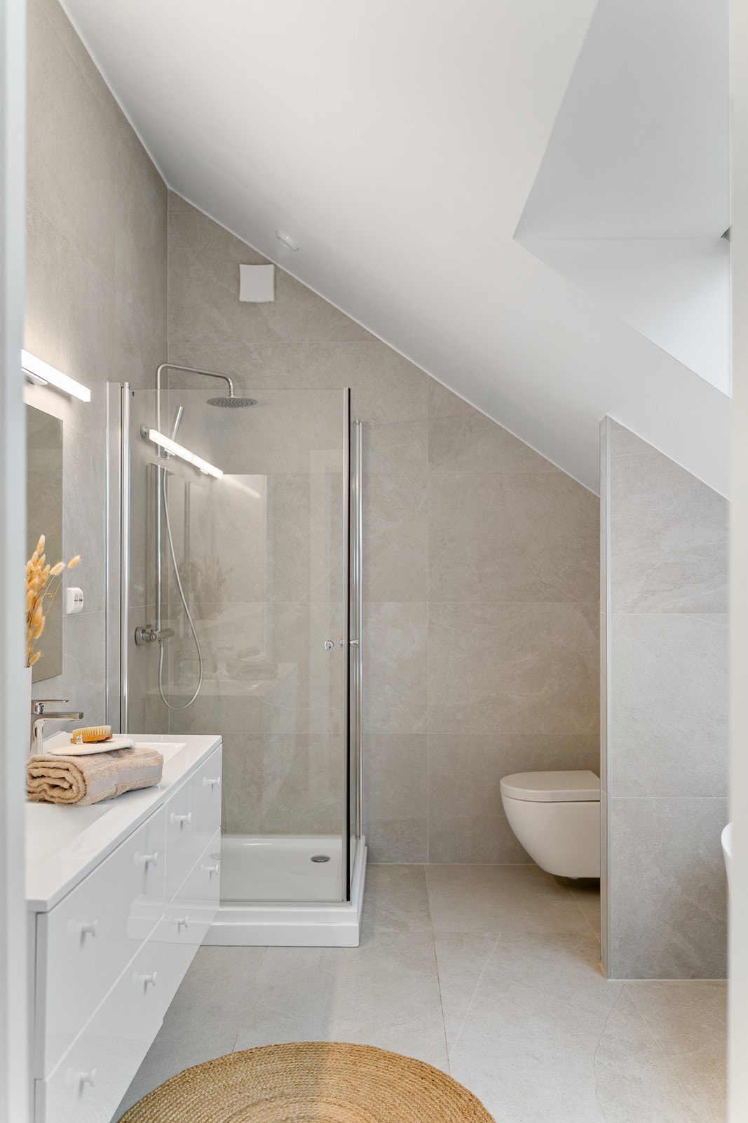 Badet er innredet med vegghengt toalett, dobbel vask i servantskap, dusjkabinett og badekar. Galleribilde