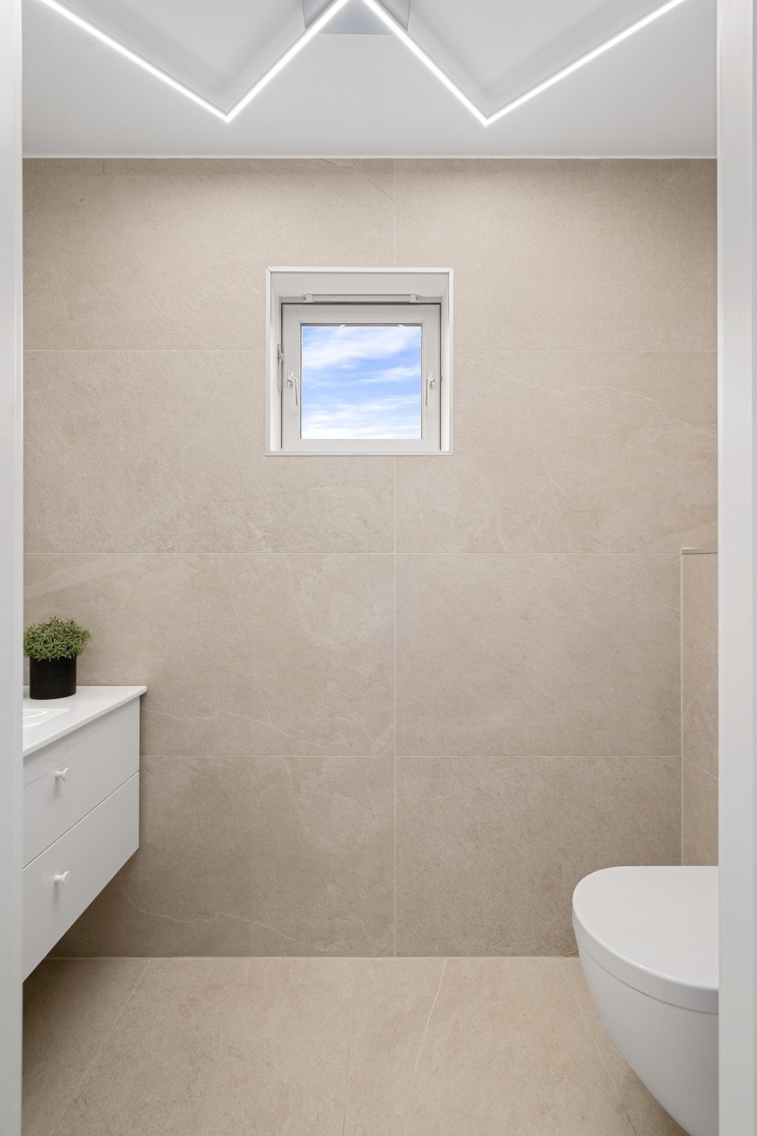 Helfliset gjestetoalett innredet med vegghengt toalett og vask i servantskap. Galleribilde