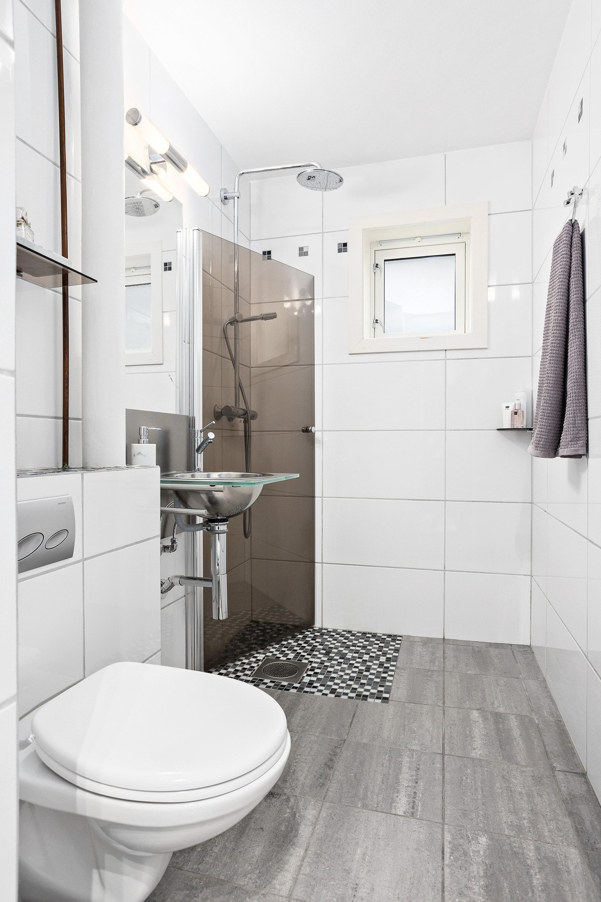 Badet fremstår som lyst og flott med flislagte vegger og gulv. Badet ble renovert i 2006 og har vegghengt toalett, dusjhjørne med glassdør og servant. Galleribilde