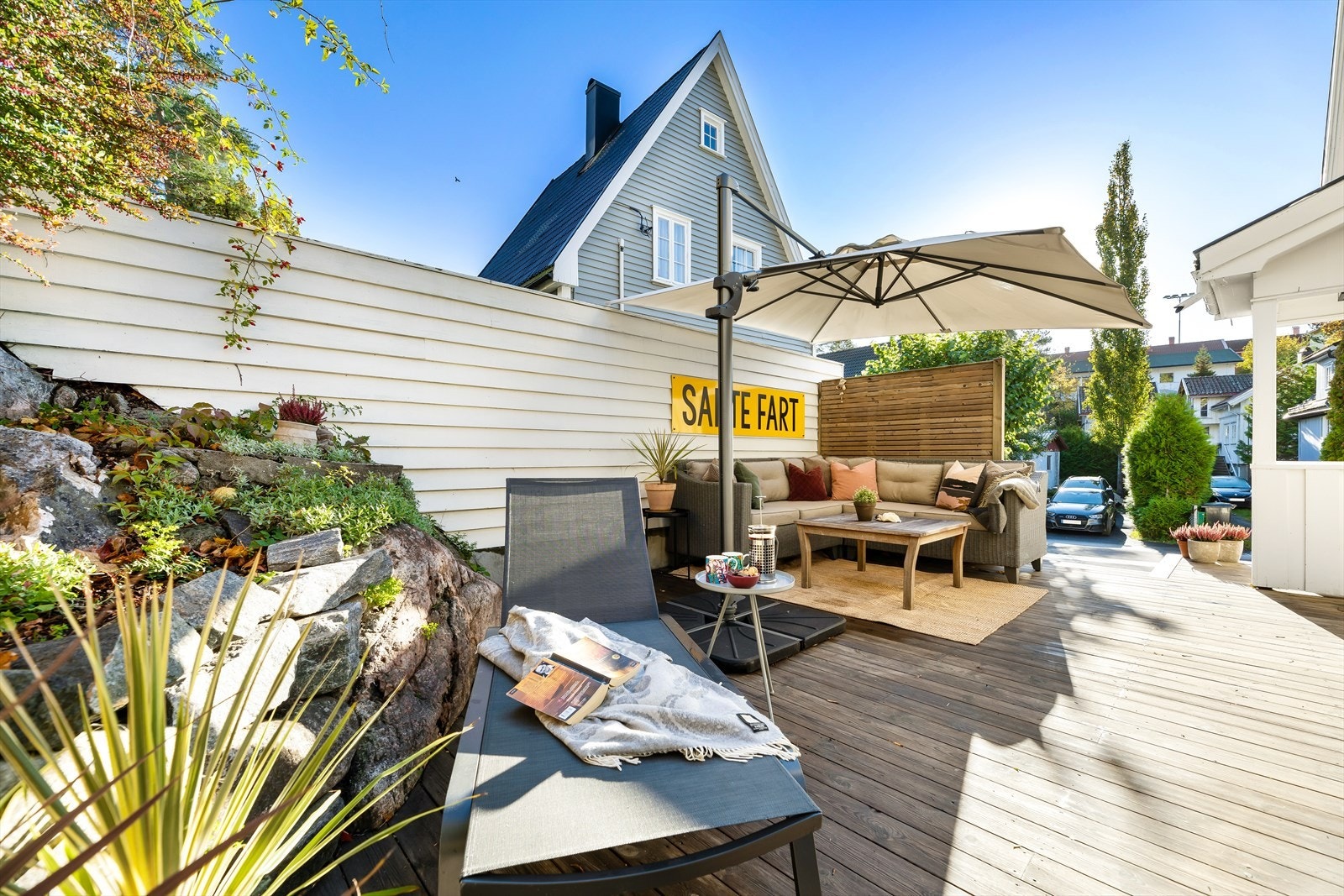 Tomten er pent opparbeidet med asfaltert innkjørsel, en liten hage, blomsterbed og en terrasse som strekker seg langs hele øst- og nordsiden av boligen. Galleribilde