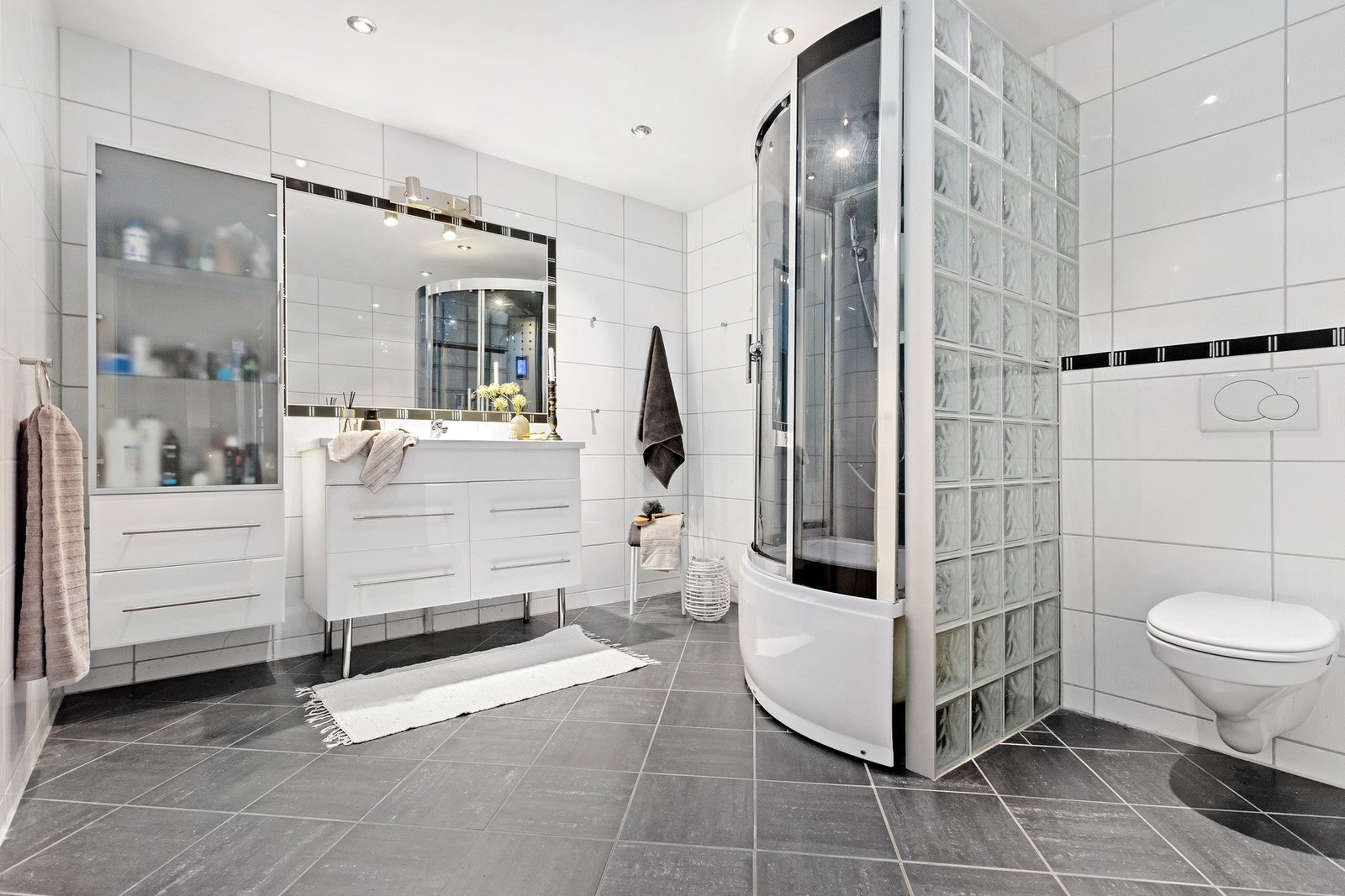 Badet er på hele 9,5 kvm og har en god utforming med tidløse flisvalg. Lukket kabinett og stor innredning Galleribilde