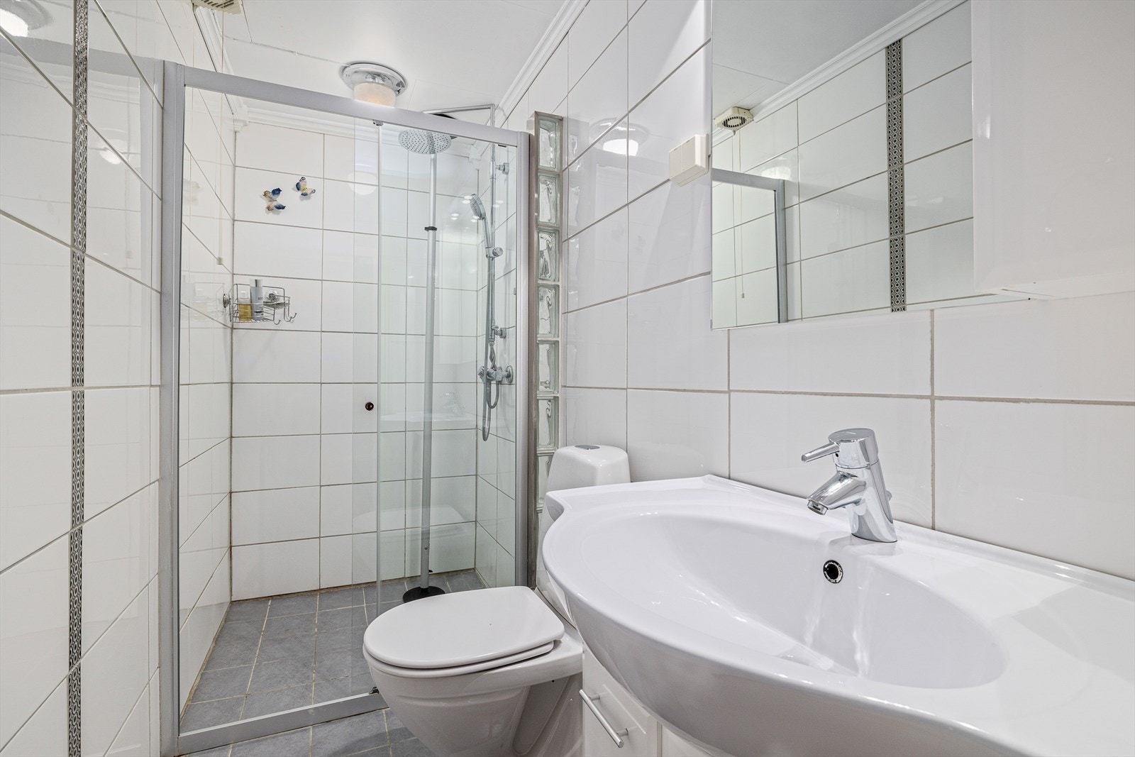 Flislagt baderom med gulvvarme, innredet med servantskap, toalett og dusj med glasskyvedør. Galleribilde