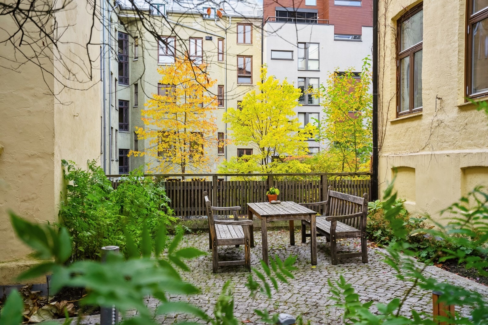 Indre gård med frodig beplantning og sittegruppe. Galleribilde