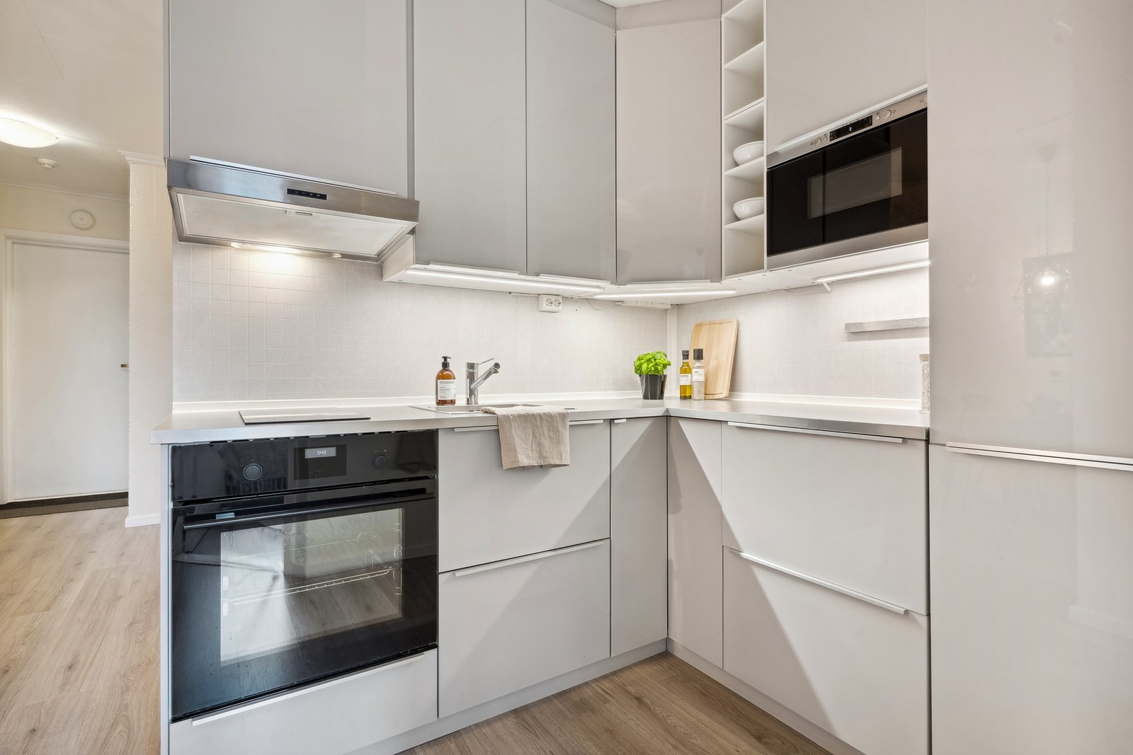 Pent kjøkken med integrert platetopp, stekeovn, kjøl/fryseskap og mikrobølgeovn. Galleribilde