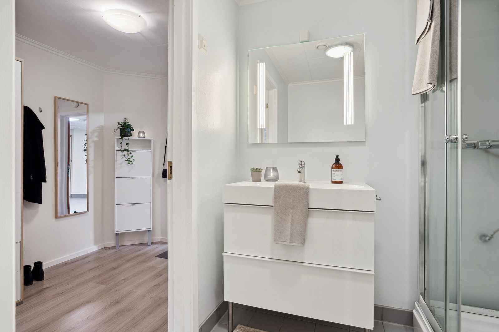 Badet er innredd med dusjkabinett, toalett, servant på underskap, speil og overskap. Galleribilde