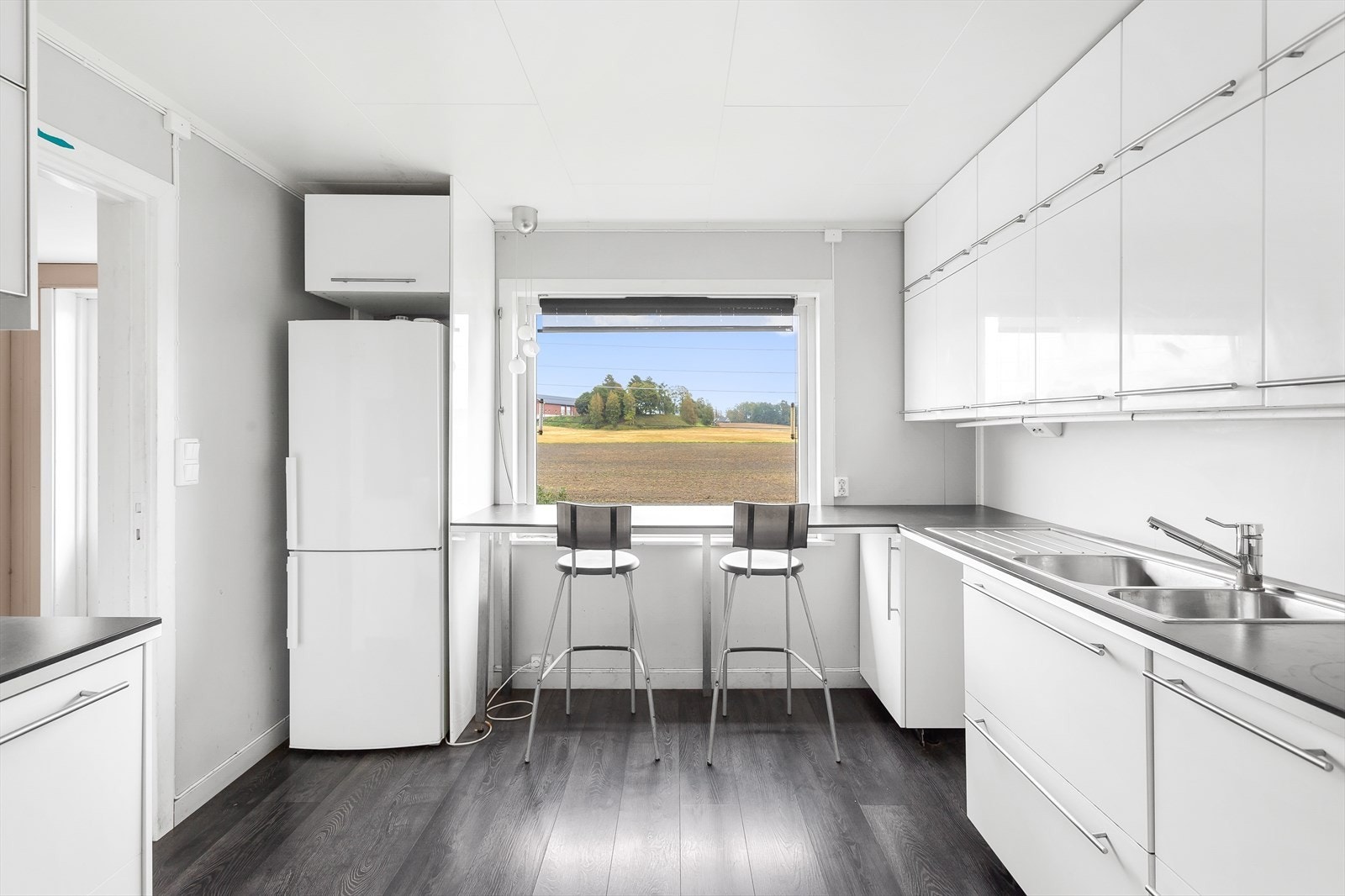 Kjøkkenet er fra 2014 og fremstår i en moderne stil. Veggene er holdt i lyse fargetoner og gulvet er i mørk, grå laminat med et rustikk preg som skaper en fin kontrast. Galleribilde