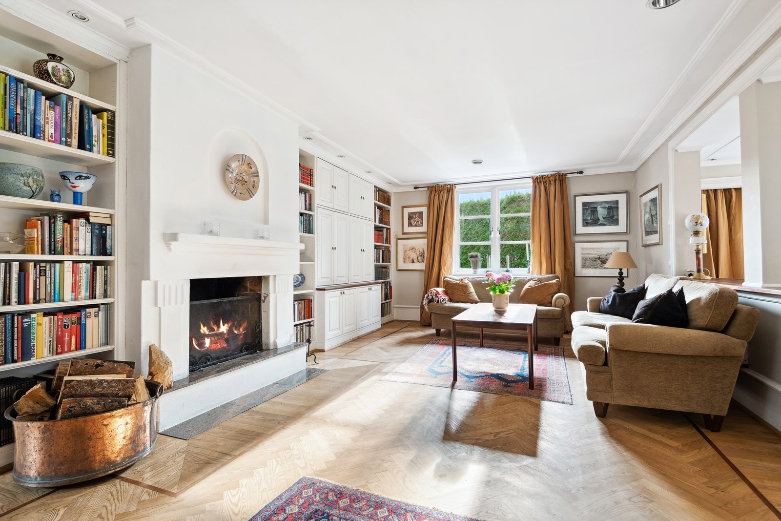 Lys og romslig TV-stue med en klassisk peis midt i rommet. Galleribilde