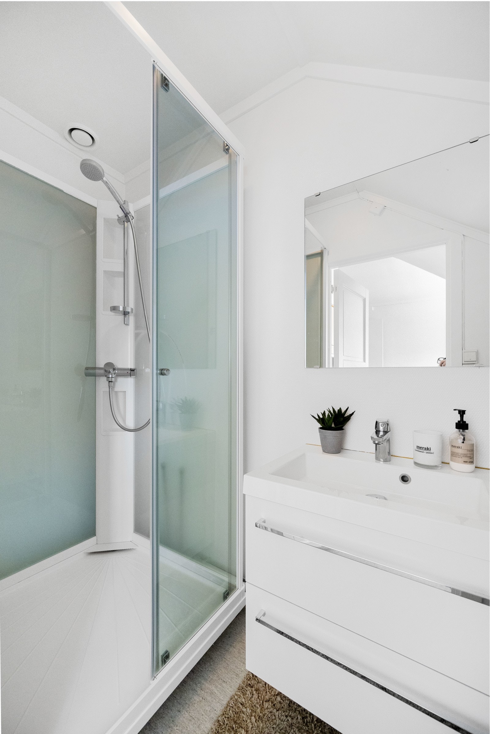 Bad innenfor kjøkken med belegg på gulv og malt strie på vegger. Badet er innredet med dusjkabinett, servant og plass til vaskemaskin Galleribilde