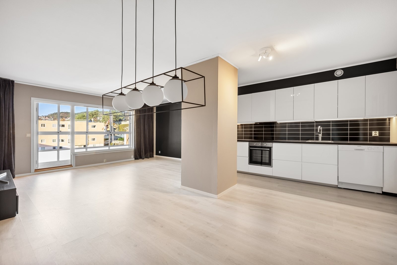 Stuen har åpen løsning mot kjøkkenet. Arealet har enstavs laminat på gulvet, malte vegger og malt betong i himling. Galleribilde