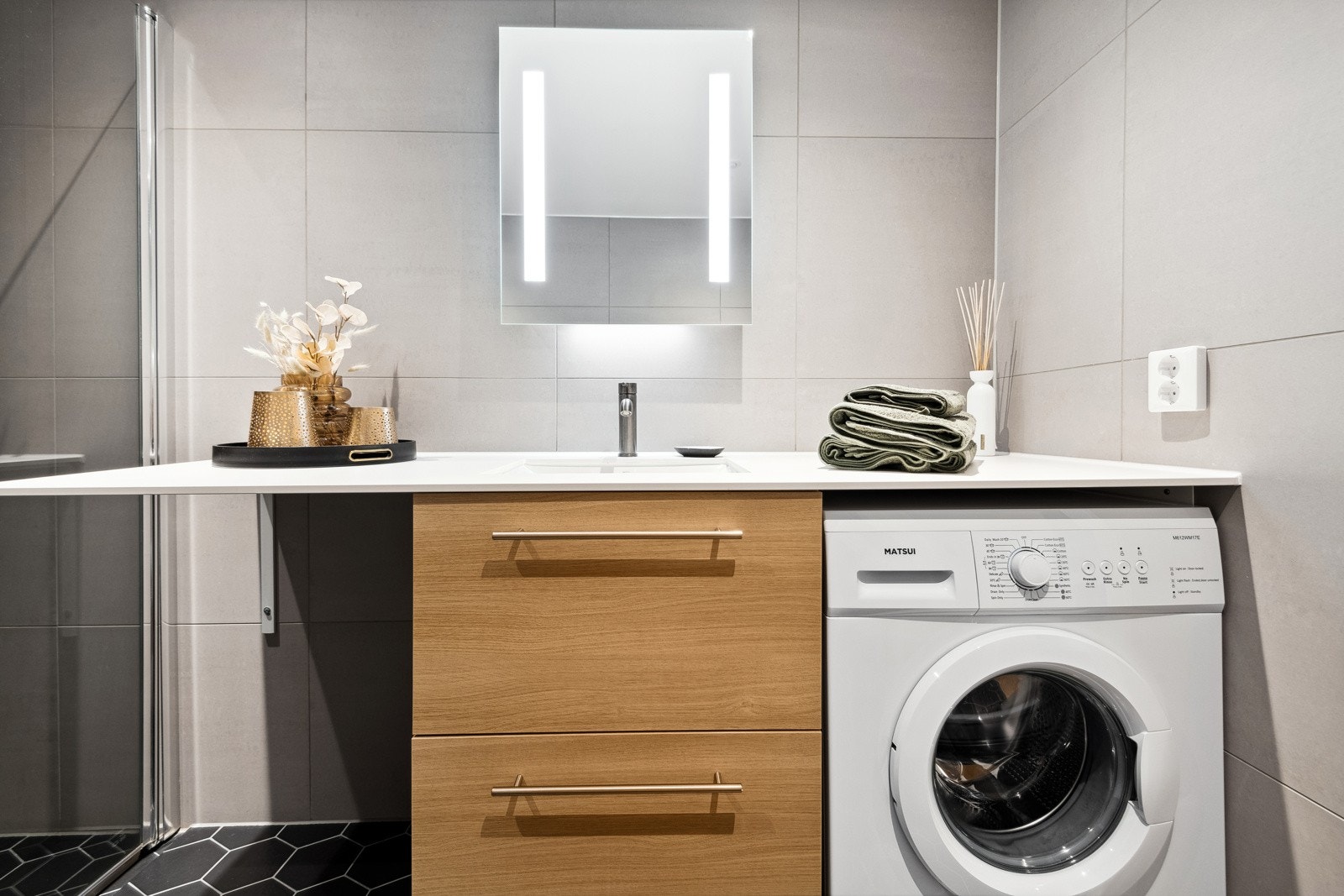 Badet er tidsmessig og helfliset, med downlights i himlingen og varme i gulvet. Her er også plass for vaskemaskin (maskinen på bildet medfølger ikke) Galleribilde