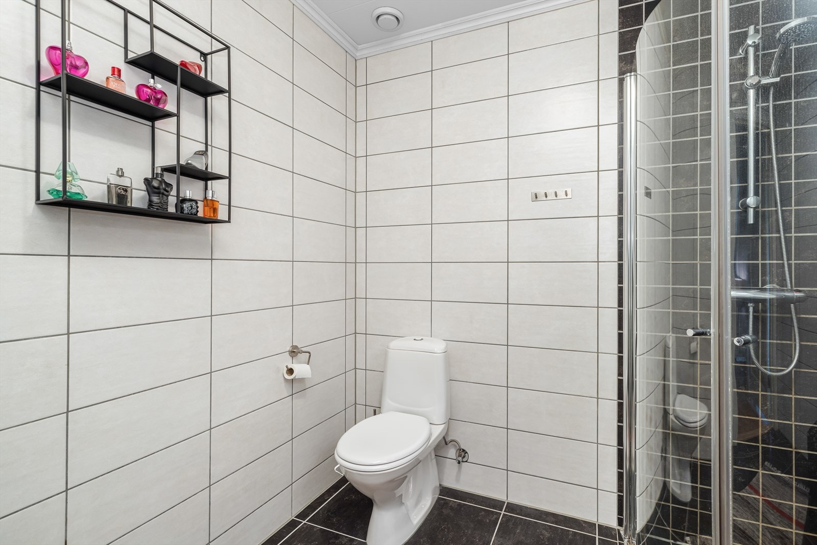 Badet har også dusjhjørne med innsvingbare dusjdører og toalett. Her er det flis på gulv og vegger. Galleribilde