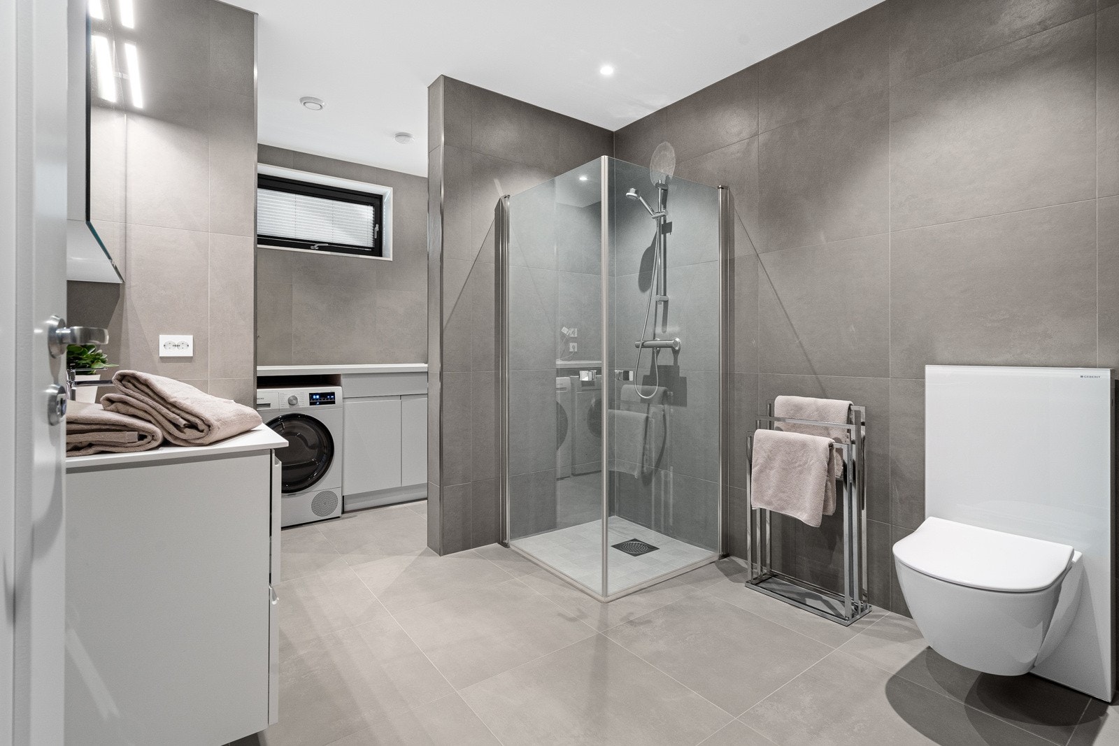 Hovedbadet/vaskerommet i 1. etasje framstår stort og er utstyrt med gulvvarme, dusjhjørne, vegghengt wc og opplegg for vaskemaskin. Galleribilde