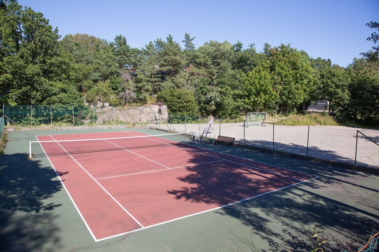 Felles tennisbane med balløkke på siden. Galleribilde