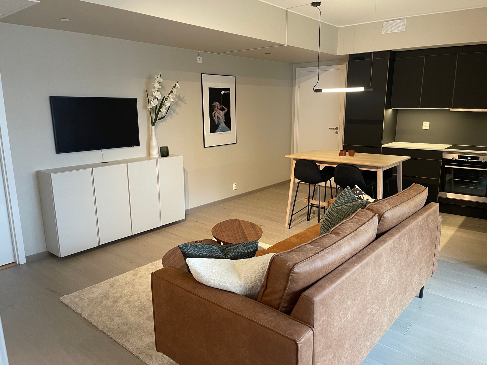 Åpen stue/kjøkkenløsning med spisebord, sofa og TV. Galleribilde