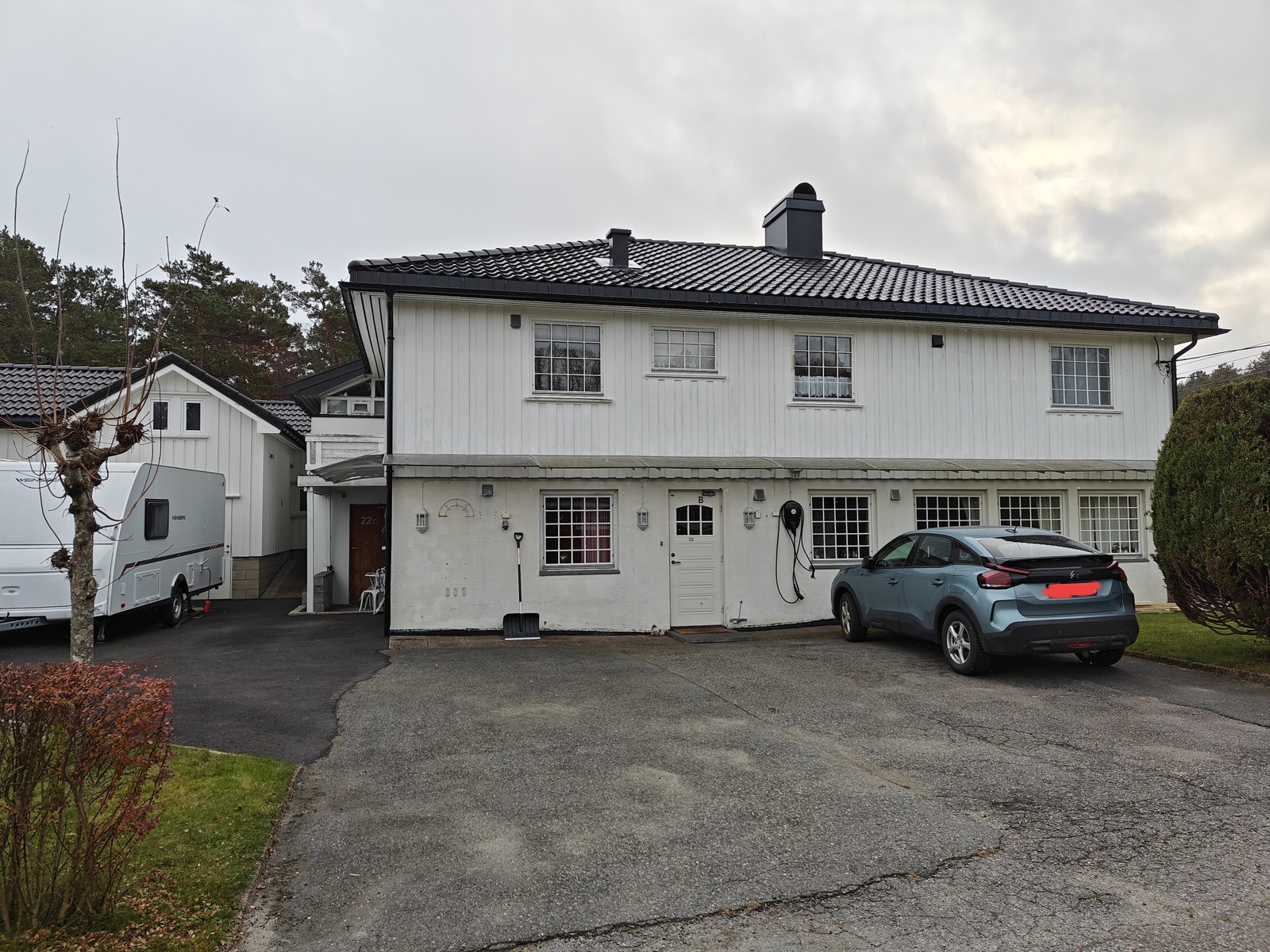 Inngangsparti (hvit inngangsdør), ladestasjon for elbil, og plass til 2 stk normale biler. Galleribilde