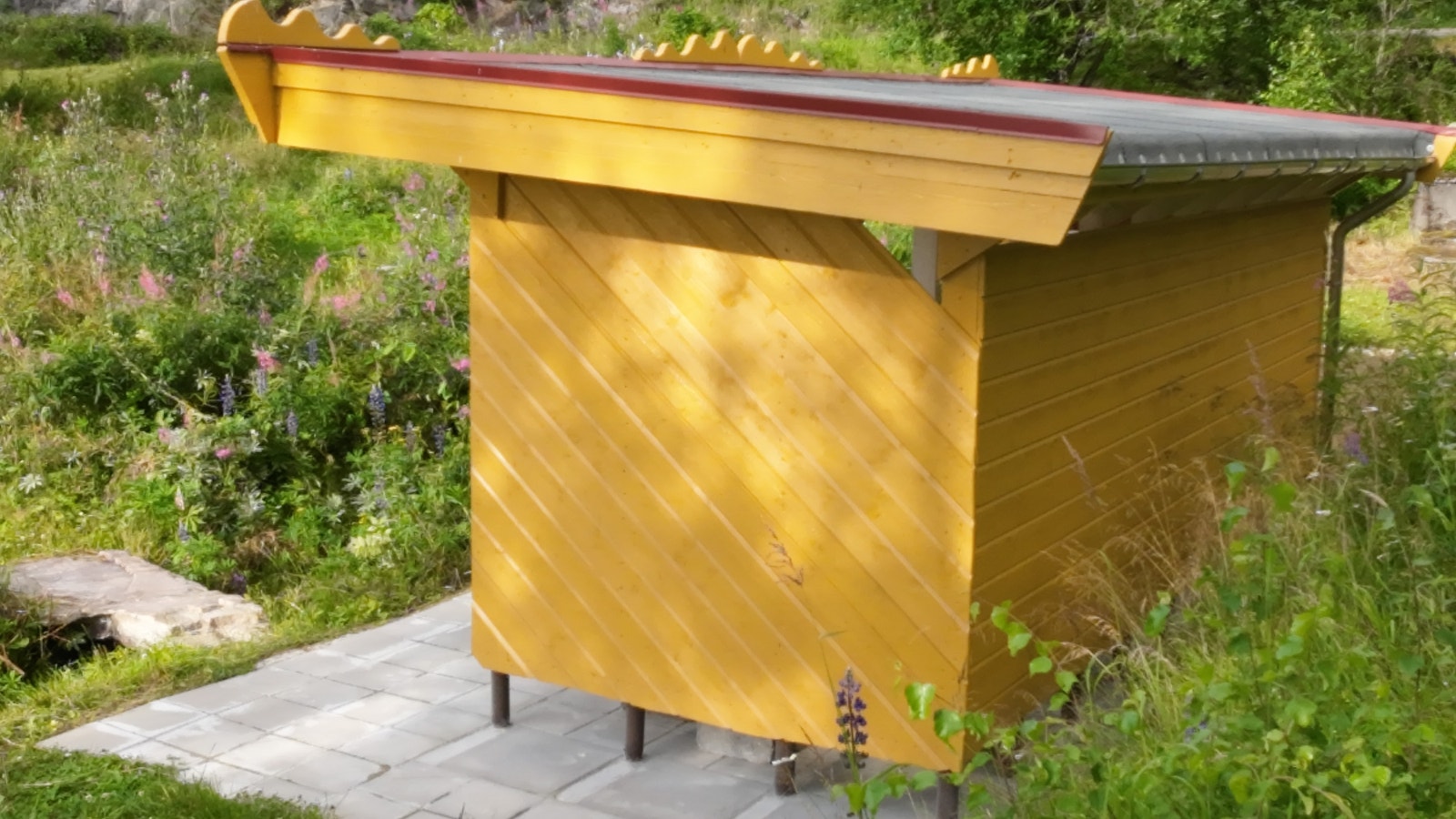 Hagestuen sett fra siden. Den er laget for å beskytte folk mot vær og vind. Galleribilde