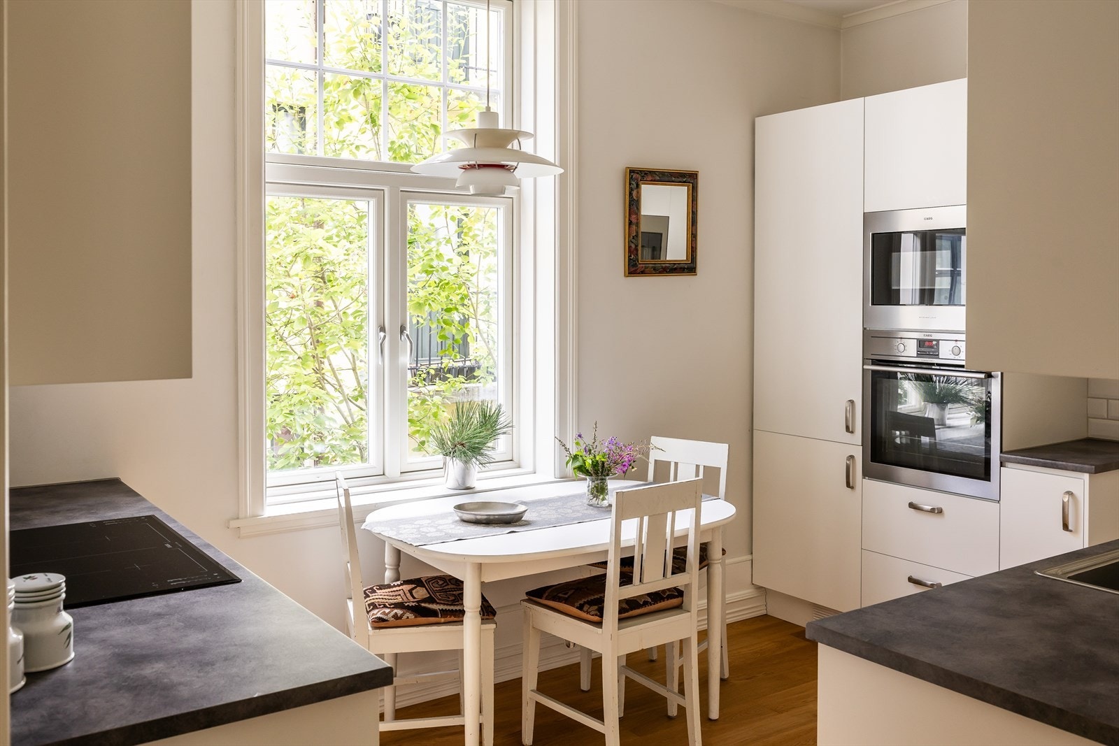 Tidløs kjøkkeninnredning (fra 2013) med glatte hvite fronter som står i stil med mørk benkeplate Galleribilde