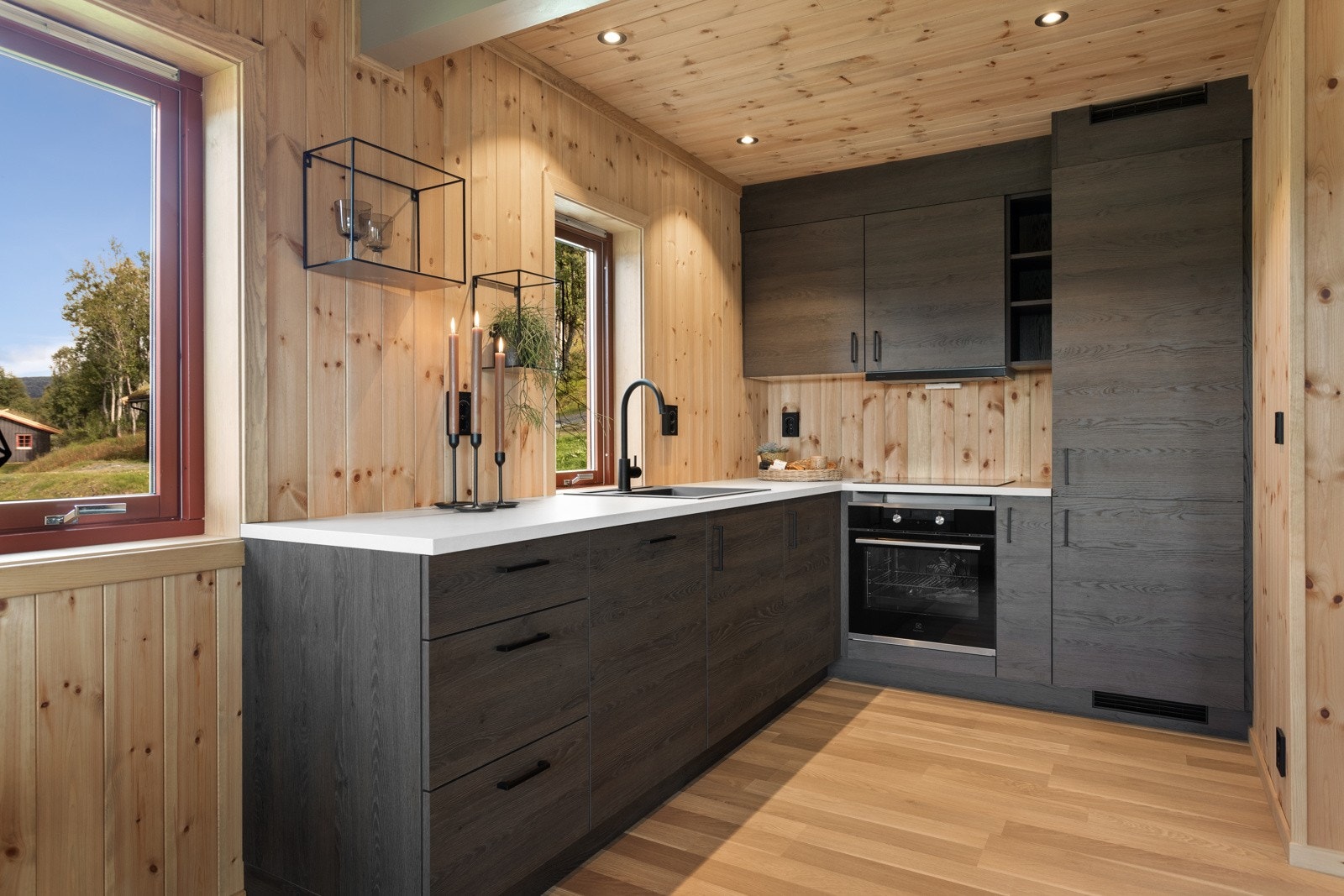 Nytt, moderne kjøkken fra Strai i vinkel med hvitevarer som kjøleskap med frysedel, komfyr, induksjonsplate, ventilator og oppvaskmaskin. Galleribilde