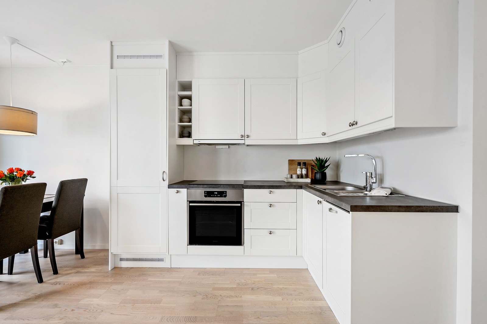 Praktisk kjøkken med integrerte hvitvarer. Slettefronter med mørk benkeplate. Galleribilde