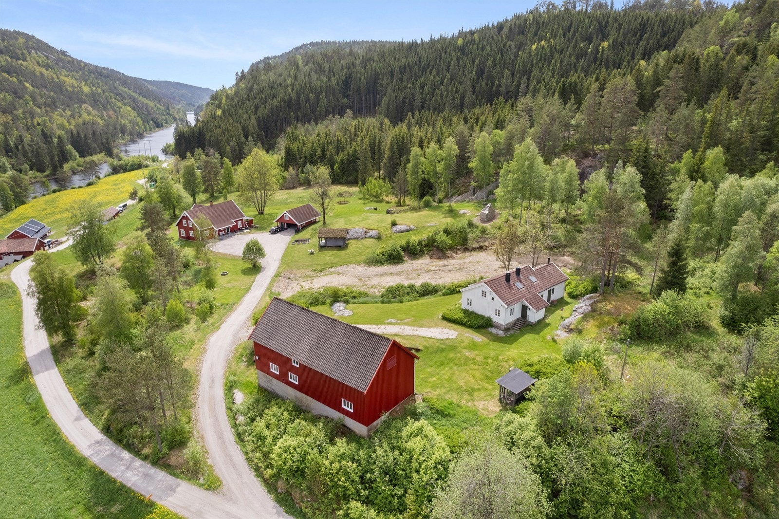 Tomten er opparbeidet med plen og prydbusker rundt huset og låven Galleribilde