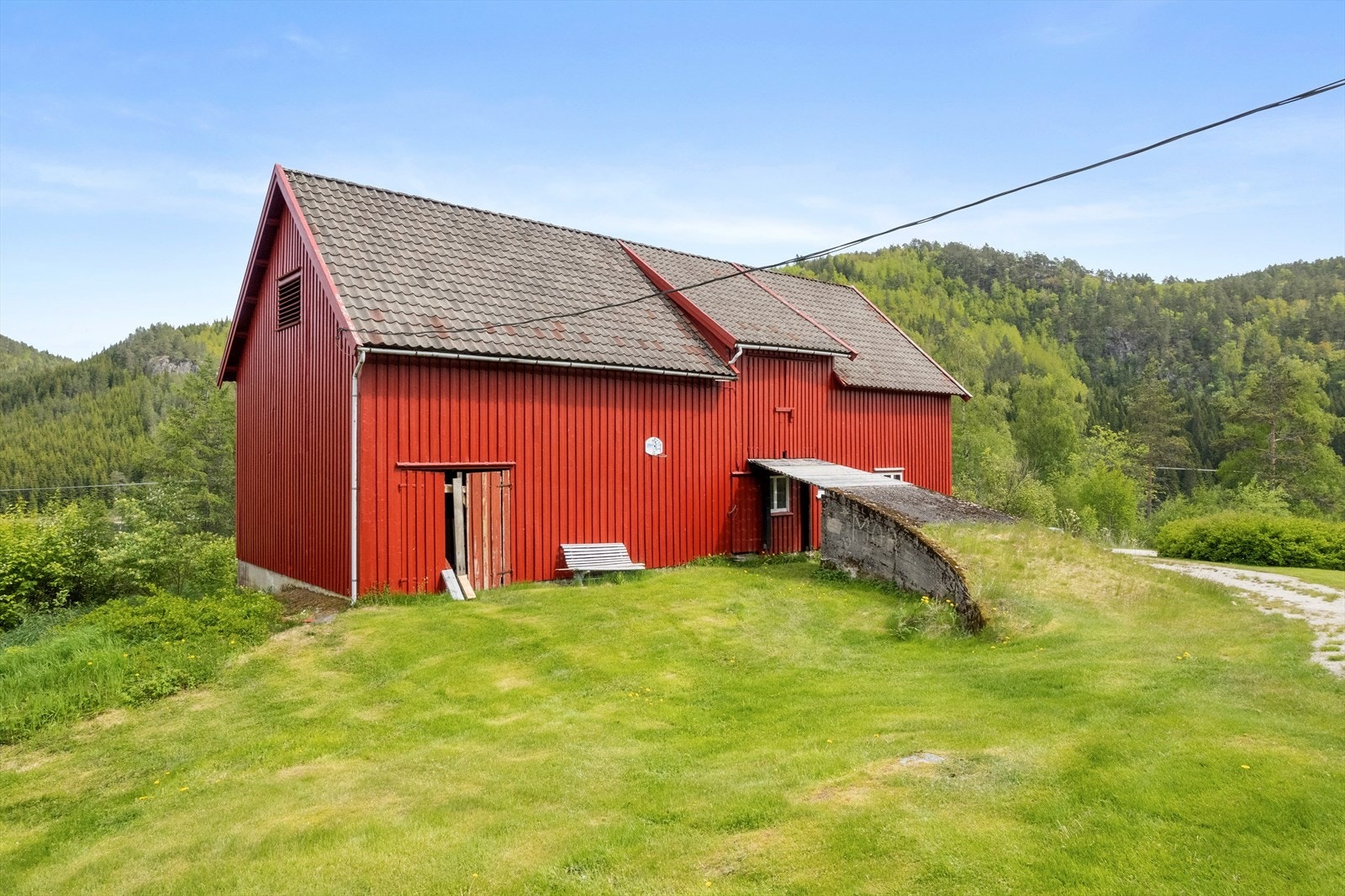 Låven har flere innganger til rom på bakkenivå og et stort loftsrom Galleribilde