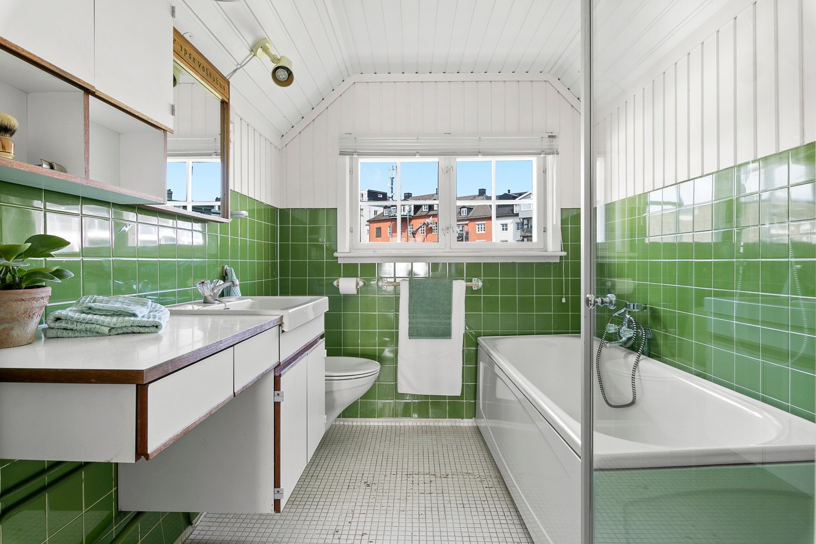 Baderom med badekar, dusj, servant med oppbevaring og toalett. Galleribilde
