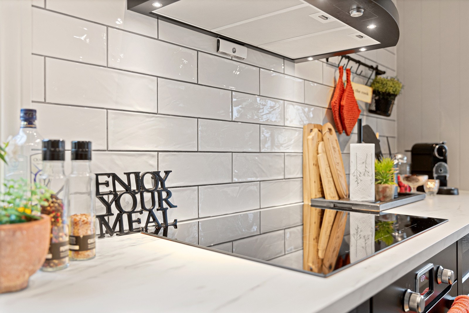 Over benken er det hvite metrofliser, benkebelysning, ventilator og komfyrvakt. Galleribilde