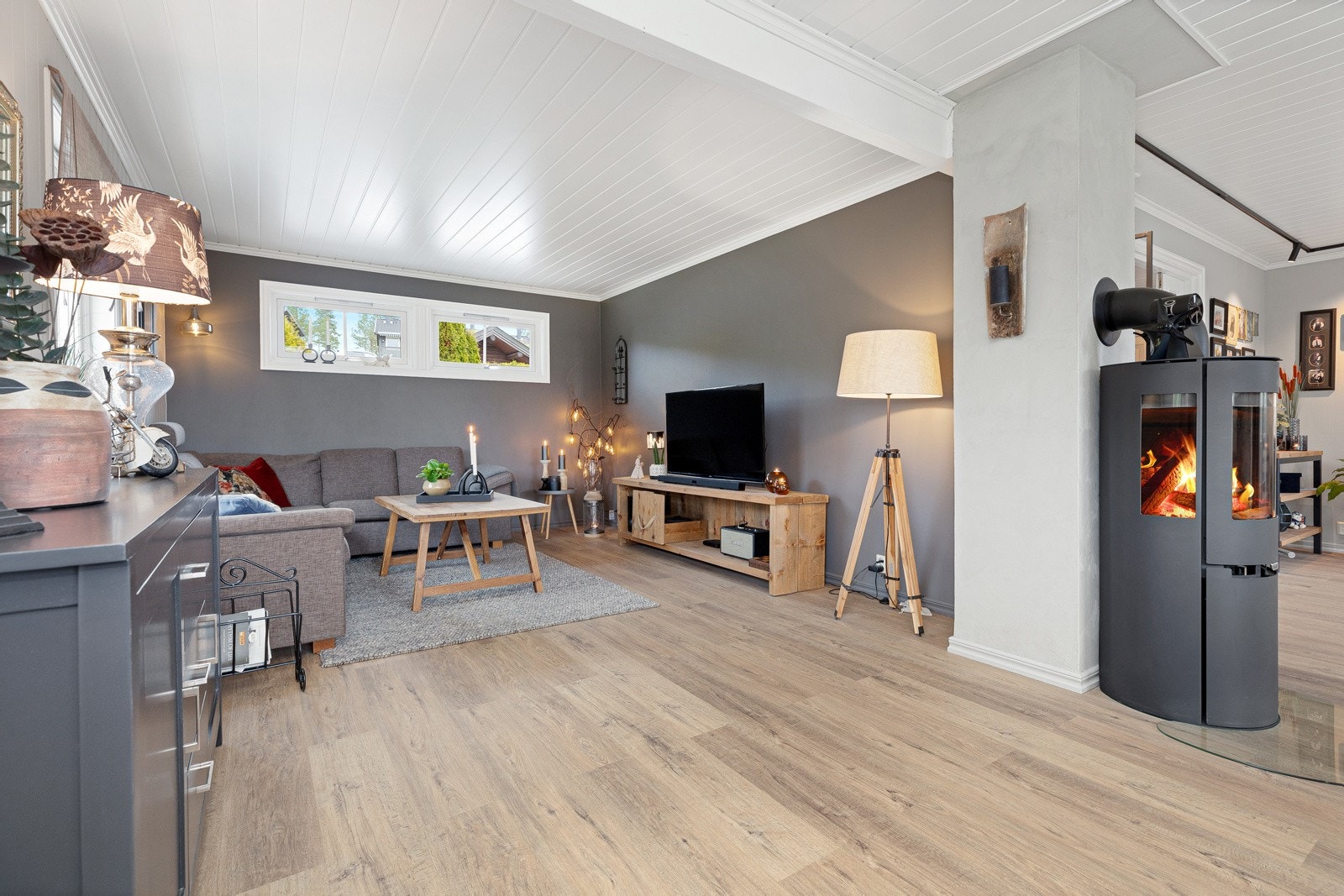 Denne delen av stuen er det plass til sofa med tv-benk og der er to av veggene malt i en mørk gråbrun farge. Galleribilde