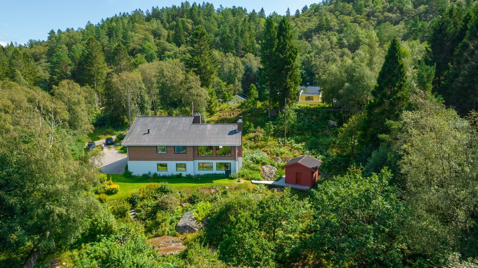 Eiendommen ligger fint i terrenget med opparbeidet område i front og resten naturtomt. Galleribilde