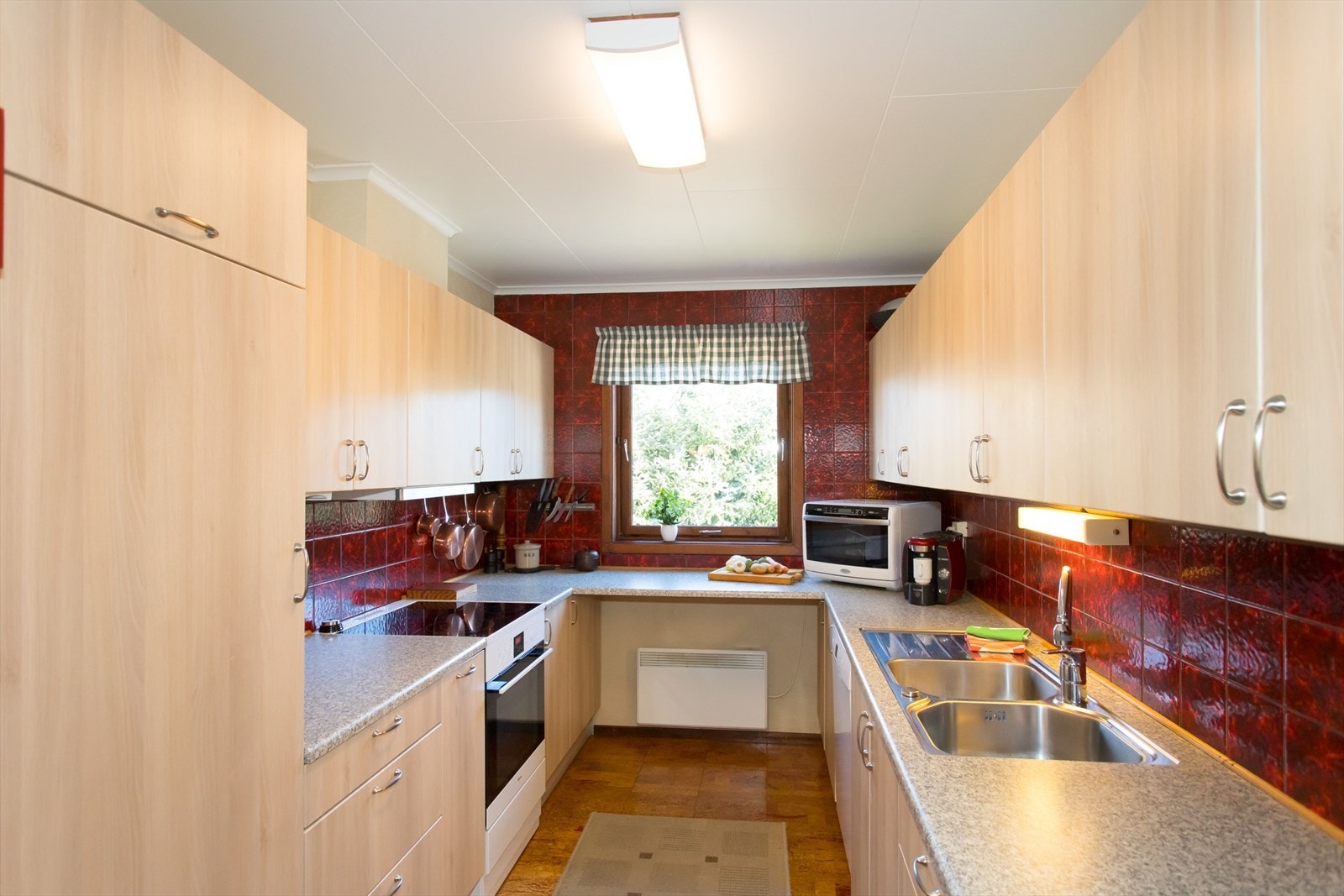 Nyere kjøkkeninnredning med glatte fronter og avsatt plass til hvitevarer som medfølger. Galleribilde