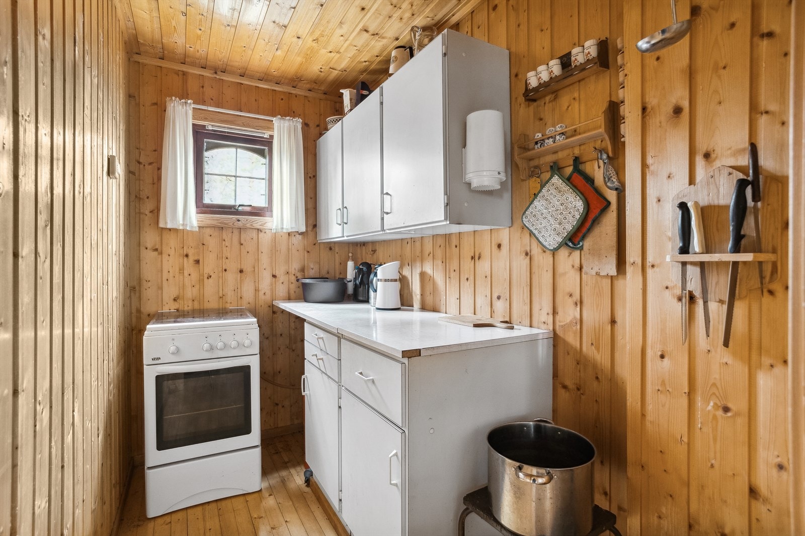 Kjøkkenkrok med lakkert tregulv, vegg og takflater er utført med trepanel. Enkel innredning med over- og underskap. Galleribilde