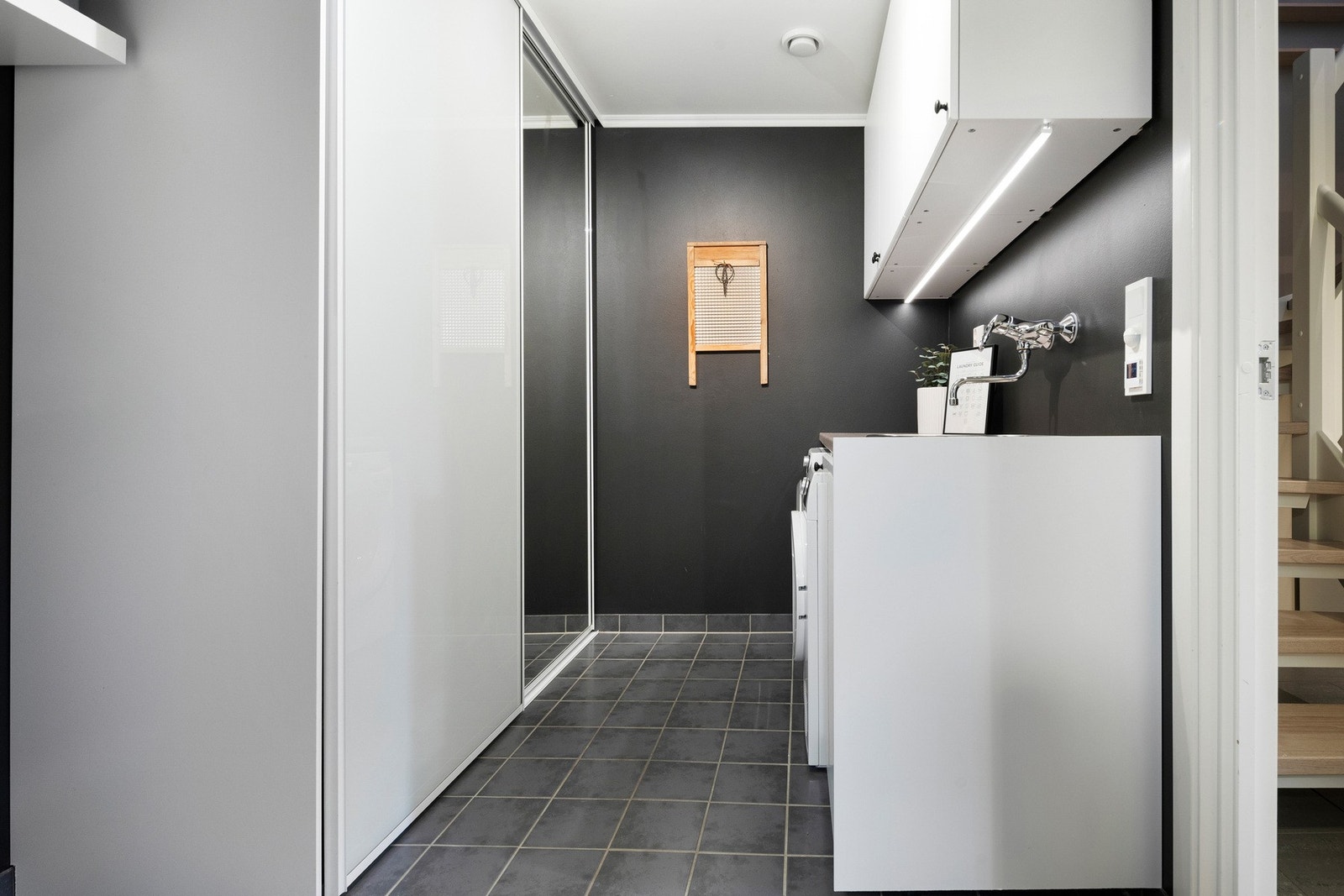 Vaskerom ved badet med skyvedørsgarderobe og skyllekum Galleribilde