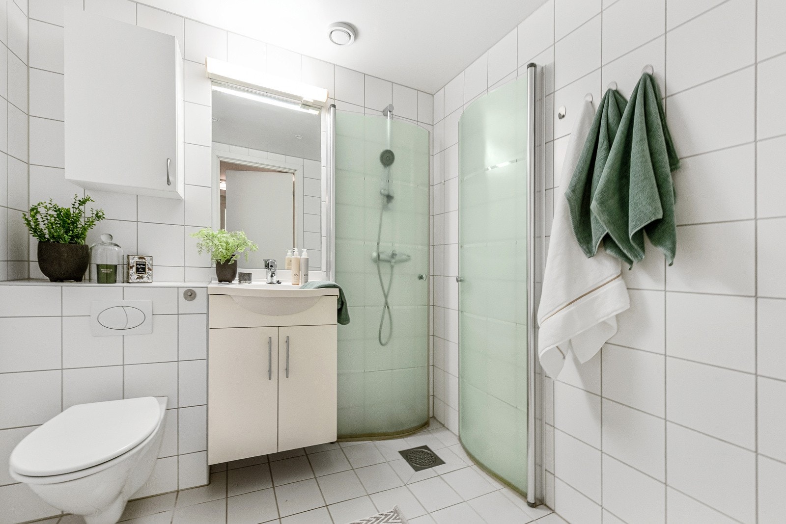 Badet er flislagt på gulv og vegger med et stilrent fargeval Galleribilde