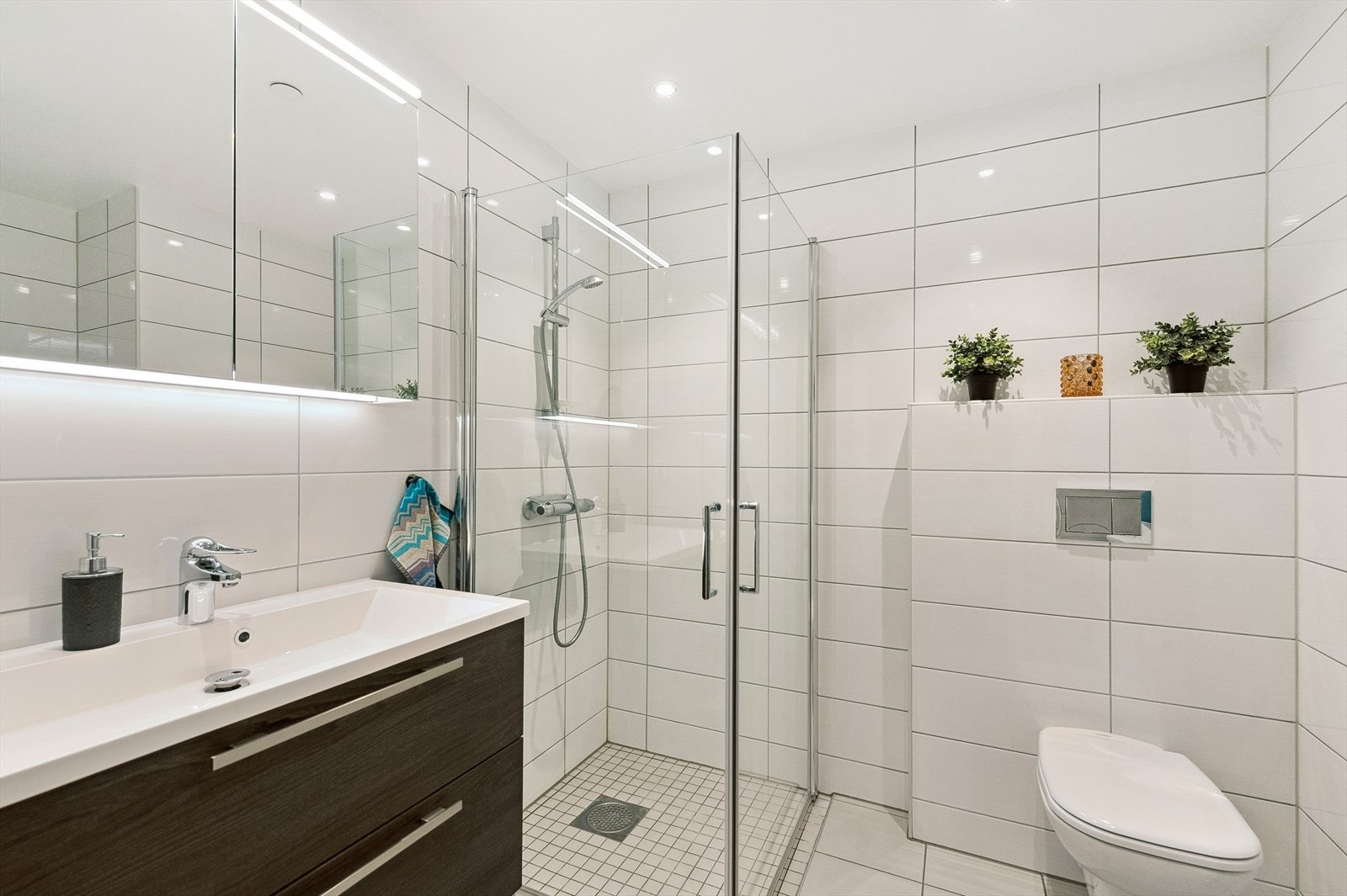 Badet har sanitærutstyr bestående av innredning med servant, veggehengt toalett og dusjhjørne. Galleribilde