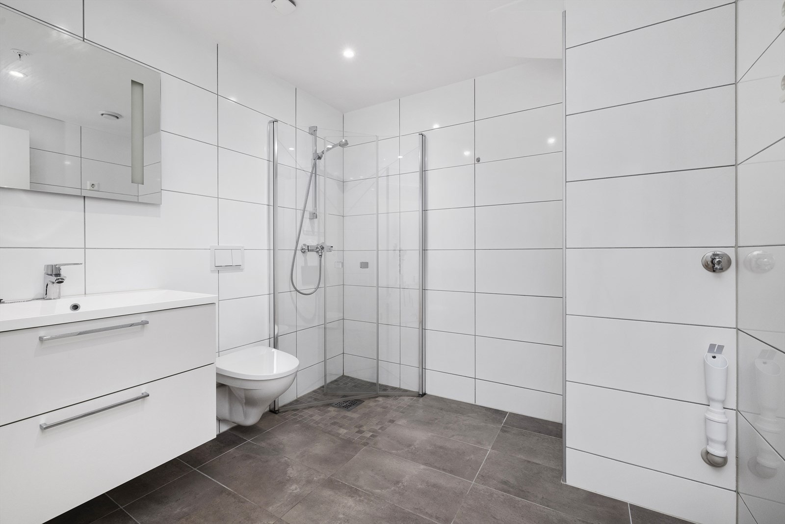 Badet er innredet med servant, dusjhjørne, vegghengt toalett og har opplegg for vaskemaskin. Galleribilde