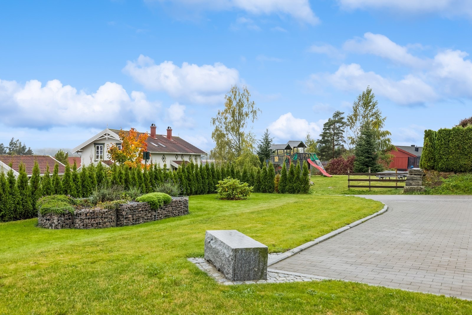 Tomten er pent opparbeidet med plen, beplantning og belegningsstein. Galleribilde