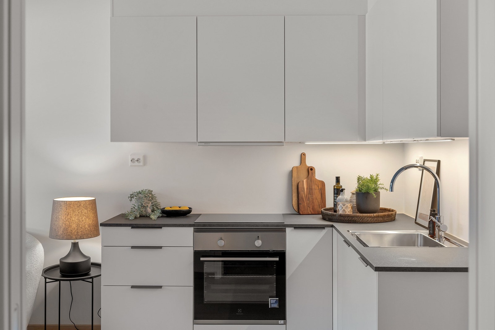 Kjøkkeninnredning med glatte fronter. Ventilator over komfyr er av type Røros hetta, tilkoblet med mekanisk avtrekk. Det er montert Waterguard i benkeskap på kjøkken Galleribilde