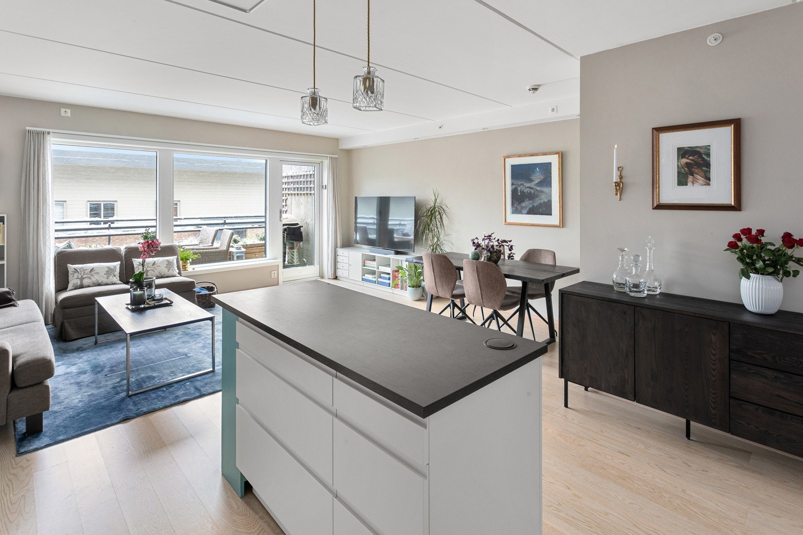 Innredningen har hvite glatte fronter og laminert benkeplate med nedfelt oppvaskkum. Praktisk med glassplate i benkeryggen, takhøye overskap med belysning under og nedfelt stikkontakt i kjøkkenøyen. Galleribilde