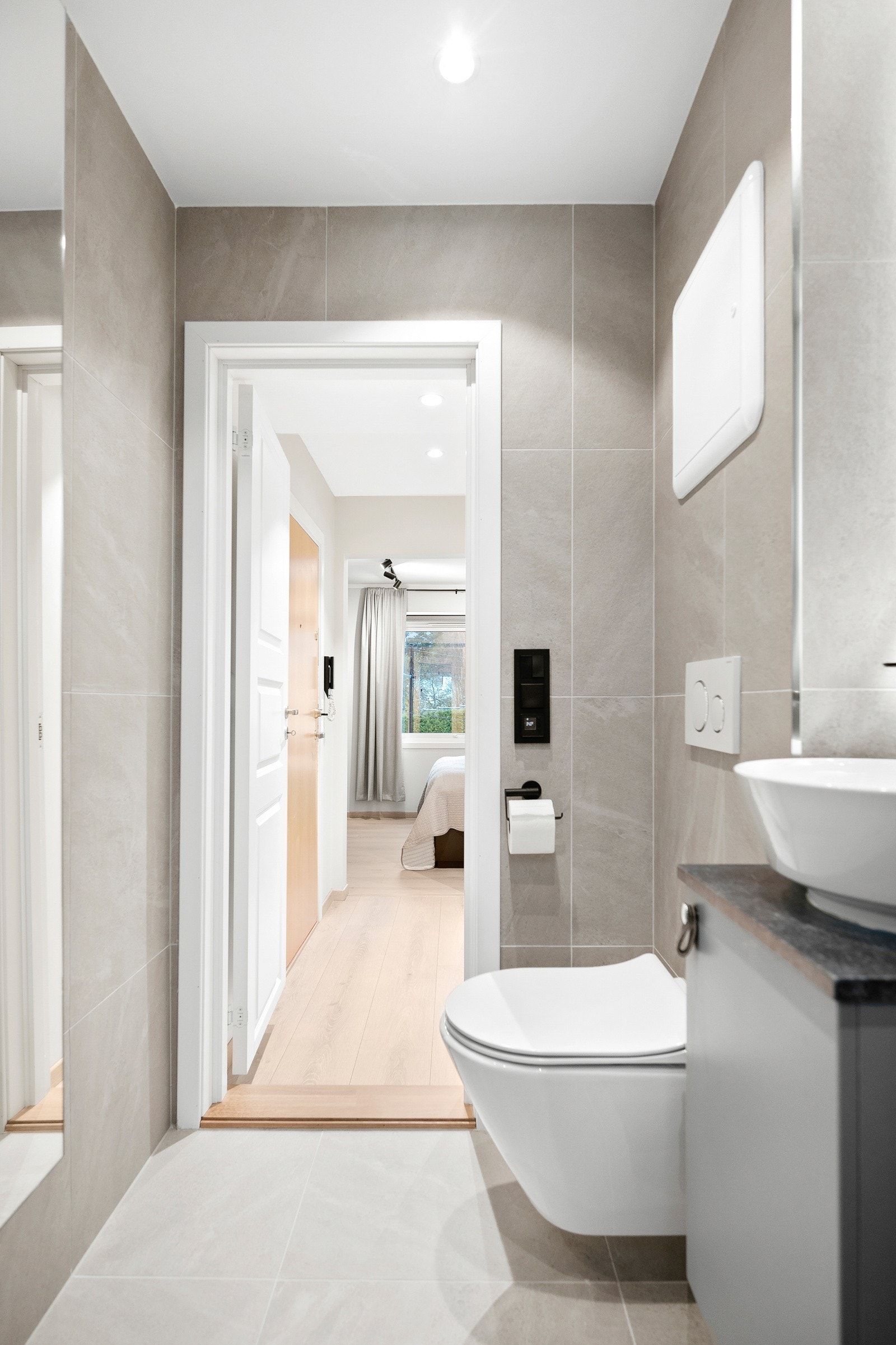 Badet er utstyrt med lekker innredning hvor du har dusjhjørne med svingbar glassdør, vegghengt toalett og servant på innredning og speil med lys. Galleribilde