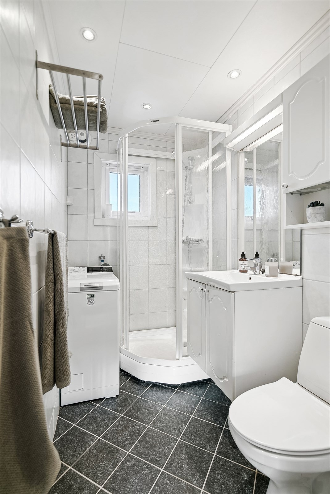 Badet er tidløst og utstyrt med dusjkabinett, servantinnredning, toalett og opplegg for vaskemaskin. Galleribilde