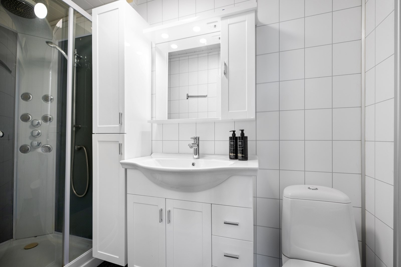 Baderomsinnredning med nedfelt servant i skapinnredning, toalett og dusjkabinett. Galleribilde