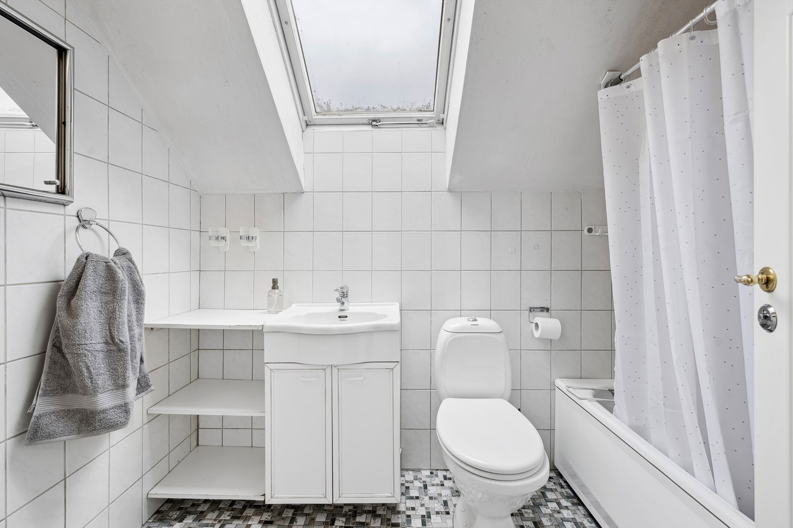 Baderom 2. etasje er av eldre dato. Det er fliser på gulv og vegger. Badet er innredet med servant, toalett og badekar med dusjmulighet. Galleribilde