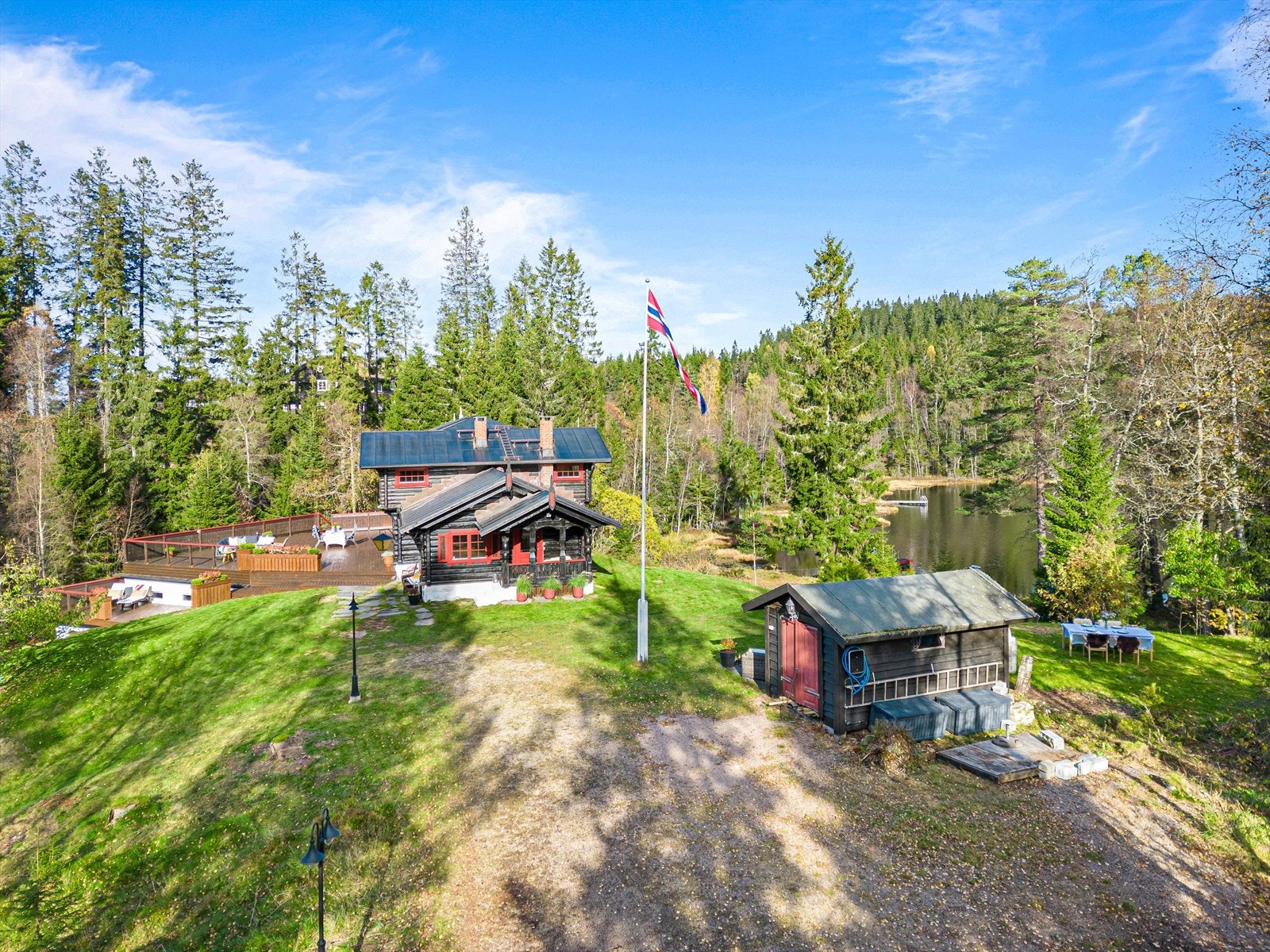 Tomten er pent opparbeidet med store, grønne plenområder, flere terrasseplattinger, gruset innkjørsel. Galleribilde