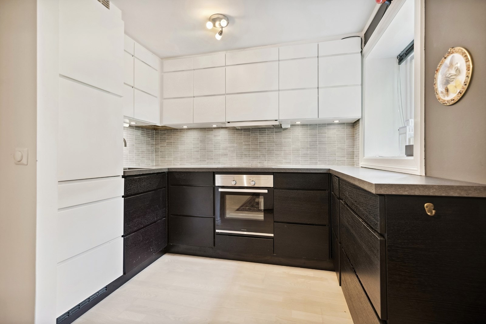 Tidsriktig kjøkkeninnredning i todelt farge med hvite matte- og brunbeisede fronter, benkeplater i laminat, underlimt oppvaskkum, ventilator og integrerte hvitevarer. Galleribilde