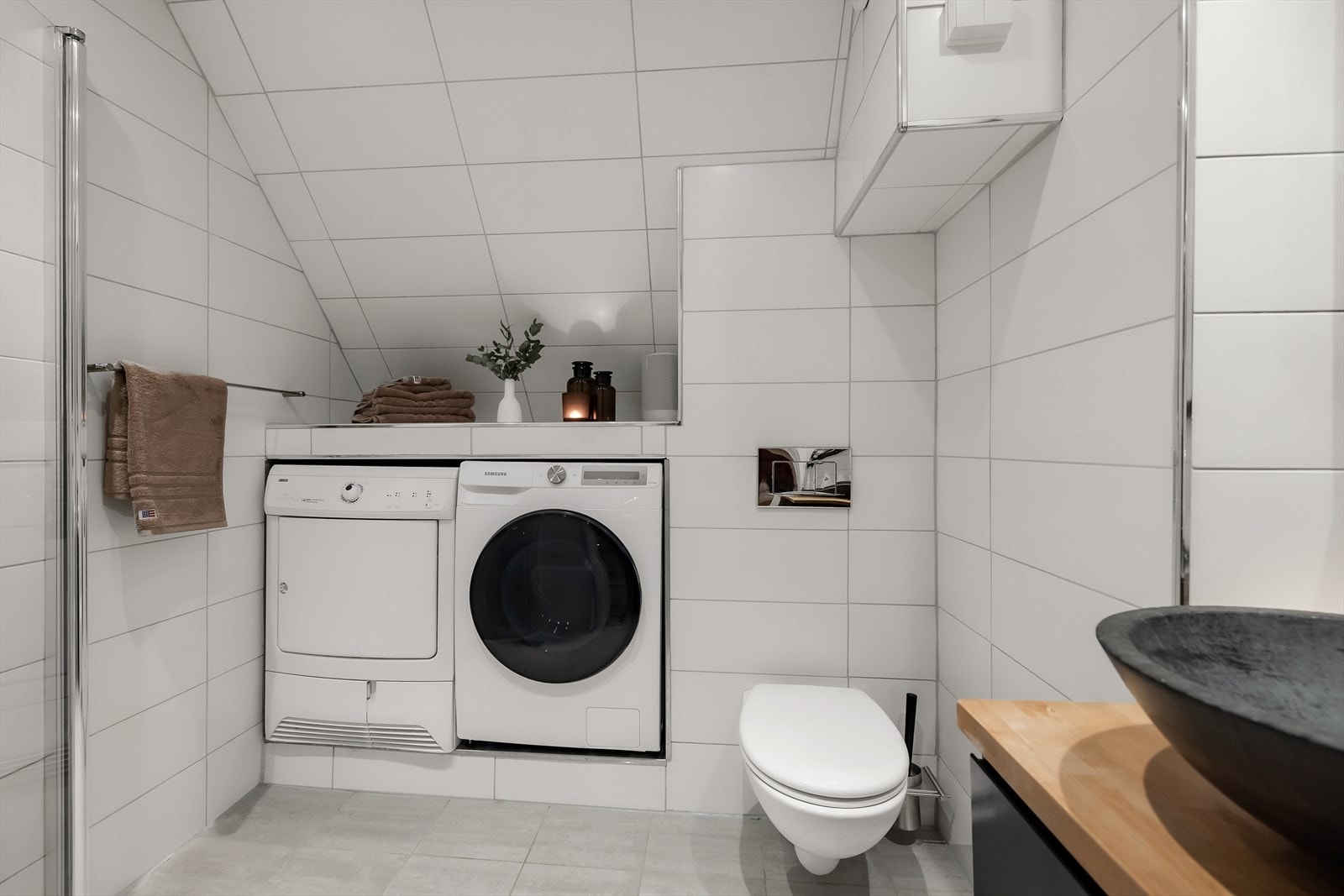 Flislagt bad med plass til vaskemaskin og tørketrommel. Galleribilde