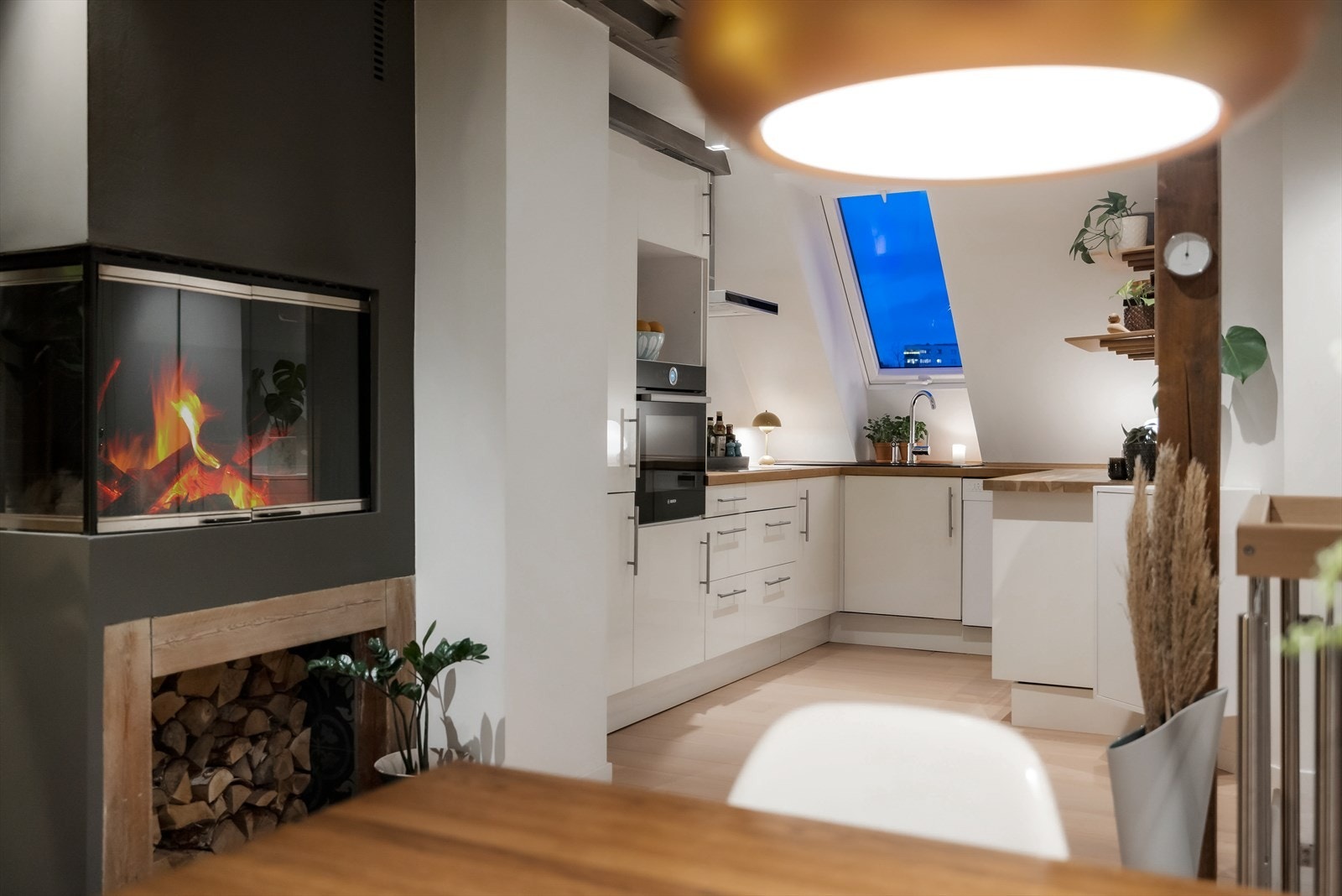 Pent kjøkken med hvit, glatt innredning med skuffer og skap. Galleribilde